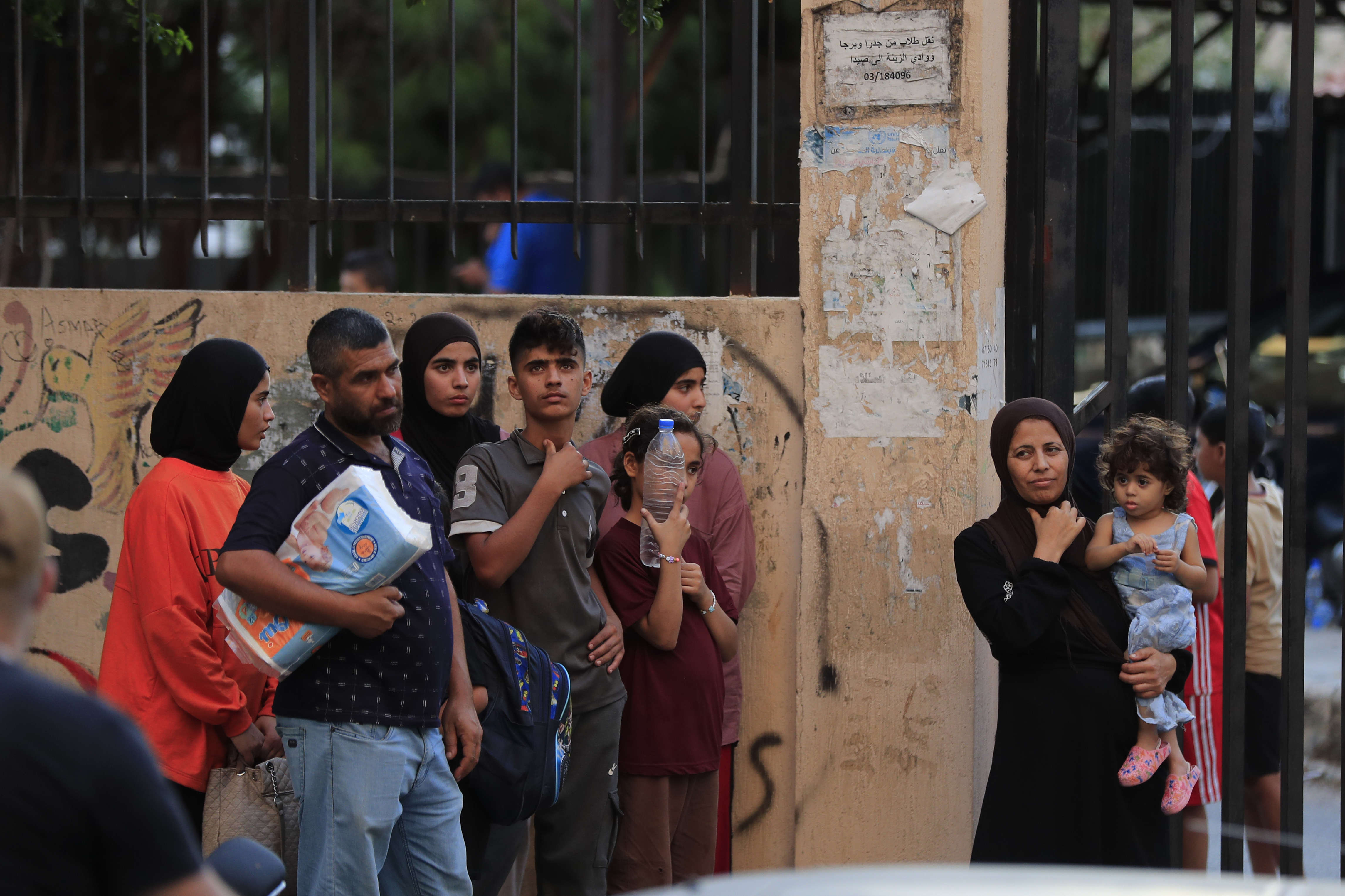 FILE - People fleeing the southern villages amid ongoing Israeli airstrikes, stand outside a school turned into a shelter in Sidon, Monday, Sept. 23, 2024. (AP Photo/Mohammed Zaatari, File)