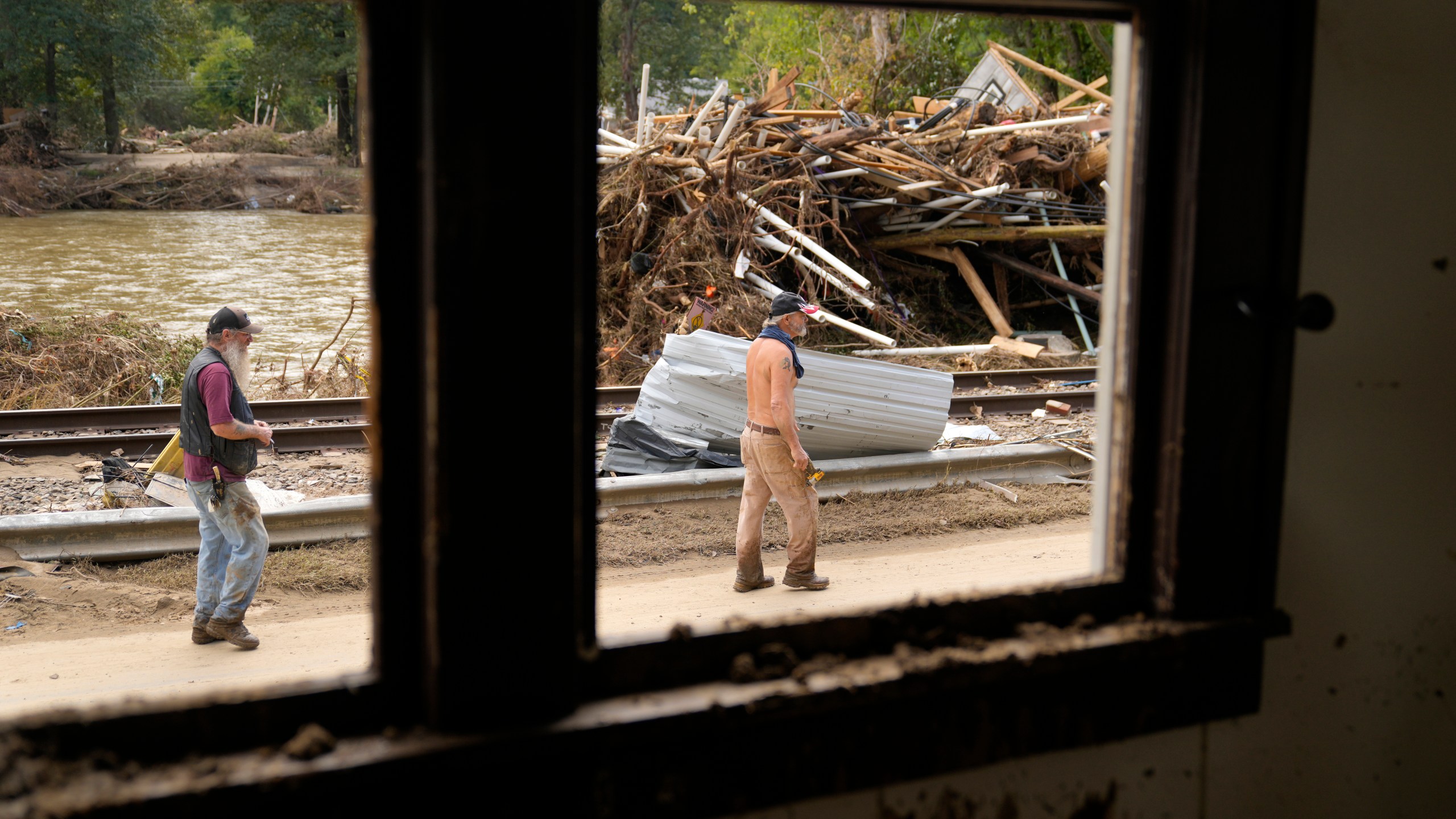 FILE - People walk by a pile of debris left in the wake of Hurricane Helene, Oct. 1, 2024, in Marshall, N.C. (AP Photo/Jeff Roberson, File)