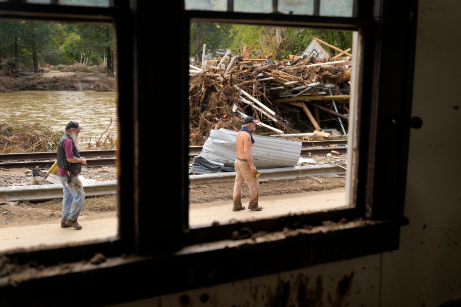 FILE - People walk by a pile of debris left in the wake of Hurricane Helene, Oct. 1, 2024, in Marshall, N.C. (AP Photo/Jeff Roberson, File)