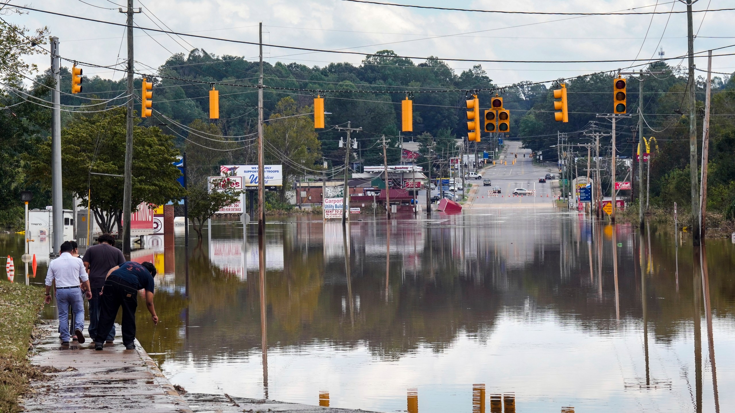 FILE - A passerby checks the water depth of a flooded road, Saturday, Sept. 28, 2024, in Morganton, N.C. (AP Photo/Kathy Kmonicek, File)