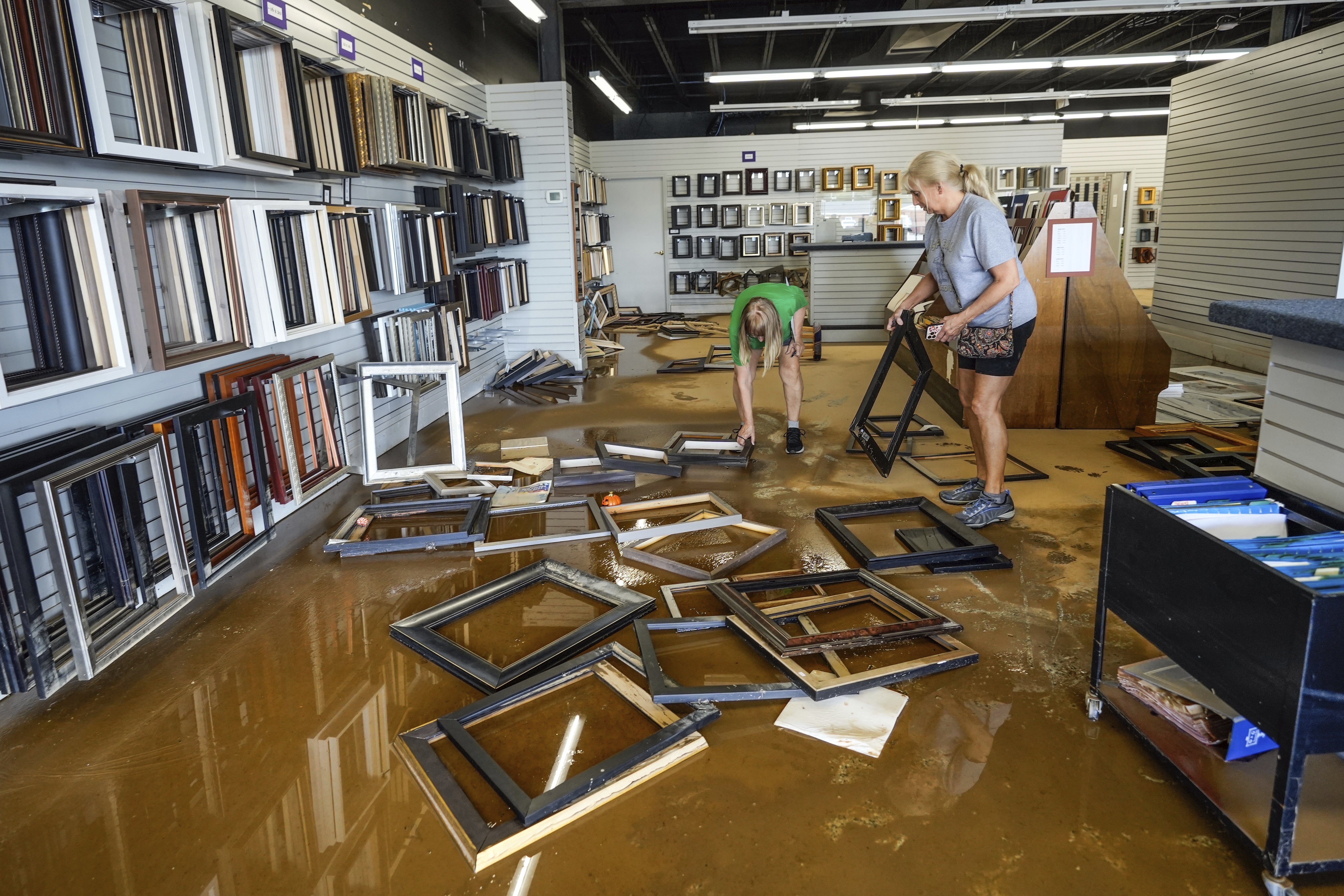 FILE - Employees Linda Bandy, left, and Carissa Sheehan clean up International Moulding frame shop damaged by floodwater from Hurricane Helene on North Green Street, Sept. 30, 2024, in Morganton, N.C. (AP Photo/Kathy Kmonicek, File)