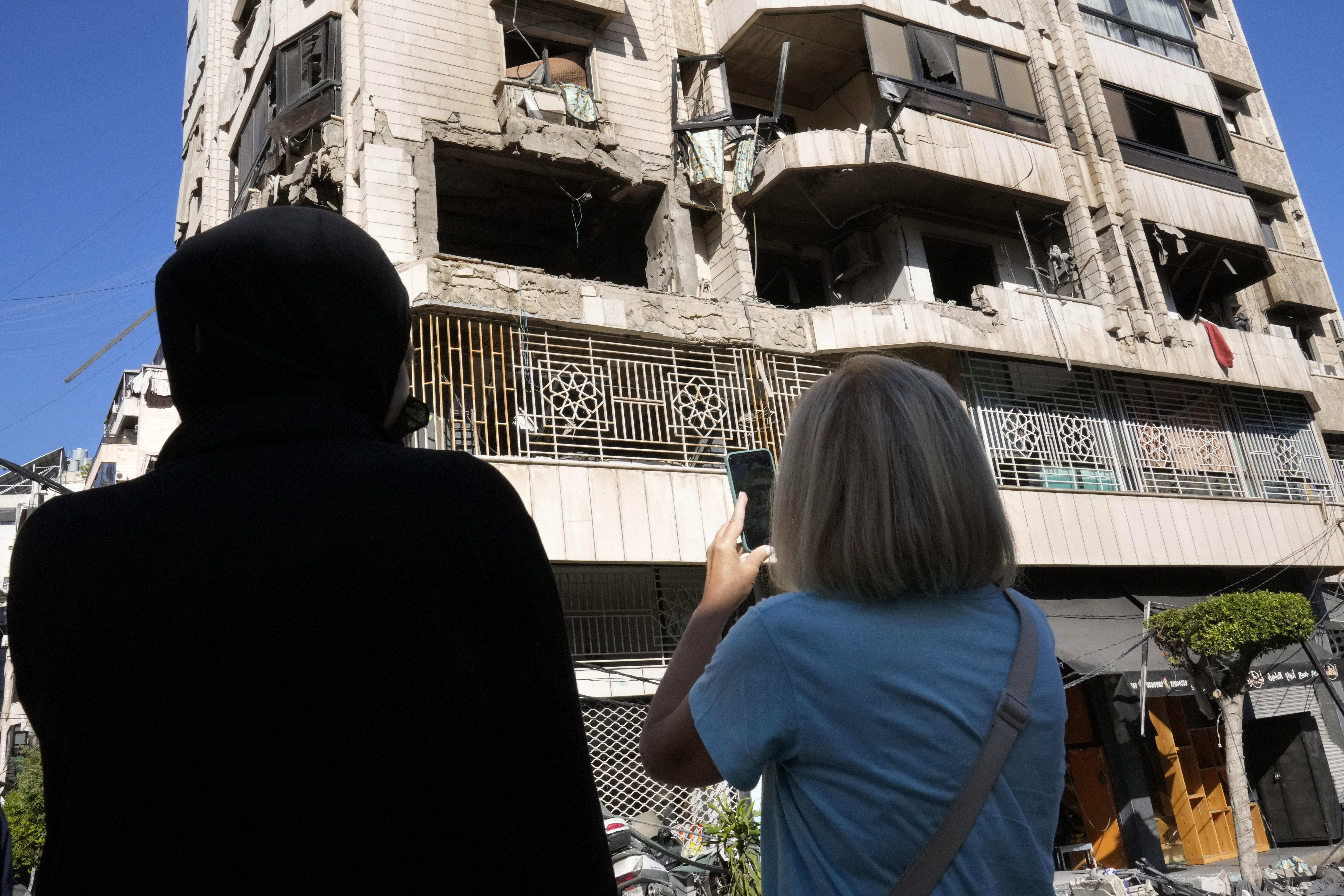 Lebanese women stand in front an apartment in a multistory building hit by Israeli airstrike, in central Beirut, Lebanon, Thursday, Oct. 3, 2024. (AP Photo/Hussein Malla)