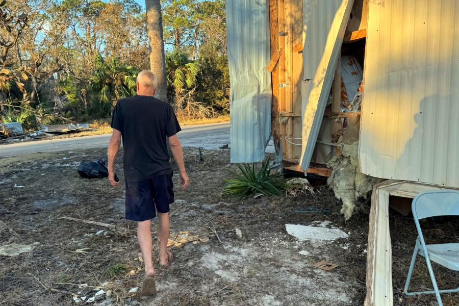 Dave Beamer walks past the partially destroyed trailer he's been living in, Sunday, Sept. 29, 2024, in Steinhatchee, Fla., after Hurricane Helene washed his home into a marsh. (AP Photo/Kate Payne)