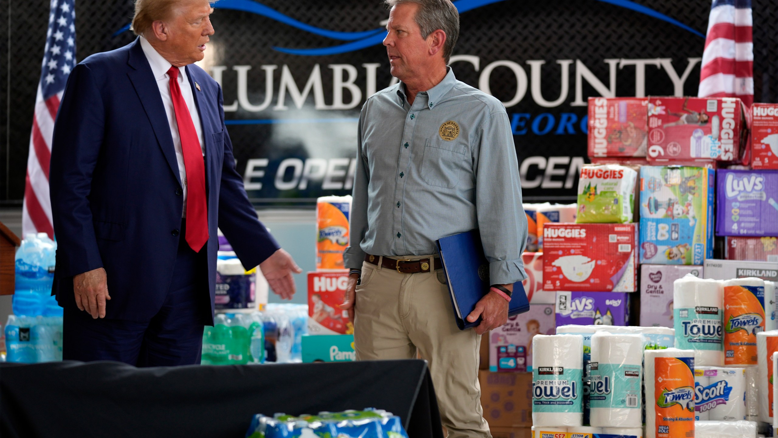 Republican presidential nominee former President Donald Trump talks with Georgia Gov. Brian Kemp after speaking at a temporary relief shelter as he visits areas impacted by Hurricane Helene, Friday, Oct. 4, 2024, in Evans, Ga. (AP Photo/Evan Vucci)