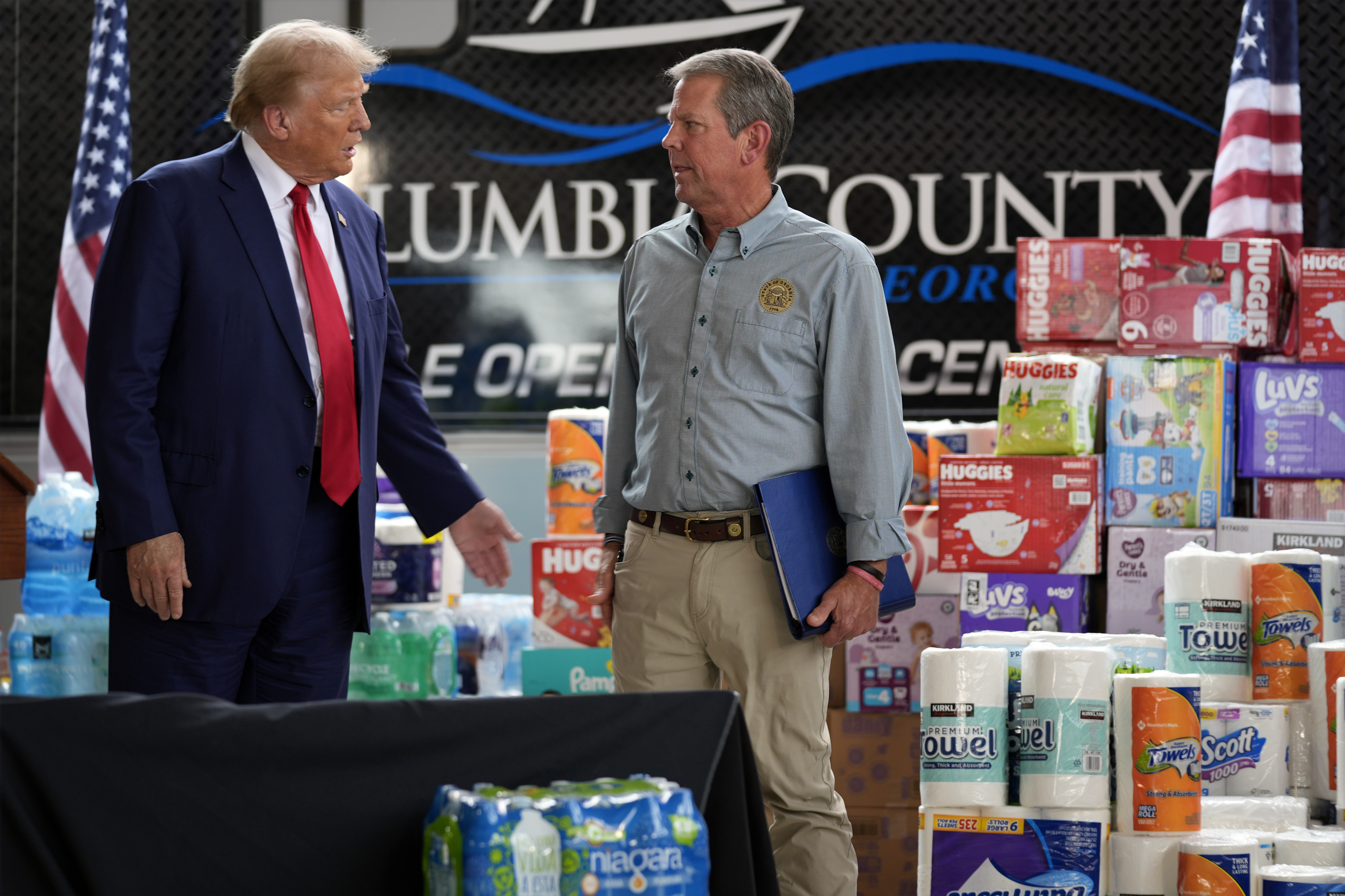 Republican presidential nominee former President Donald Trump talks with Georgia Gov. Brian Kemp after speaking at a temporary relief shelter as he visits areas impacted by Hurricane Helene, Friday, Oct. 4, 2024, in Evans, Ga. (AP Photo/Evan Vucci)