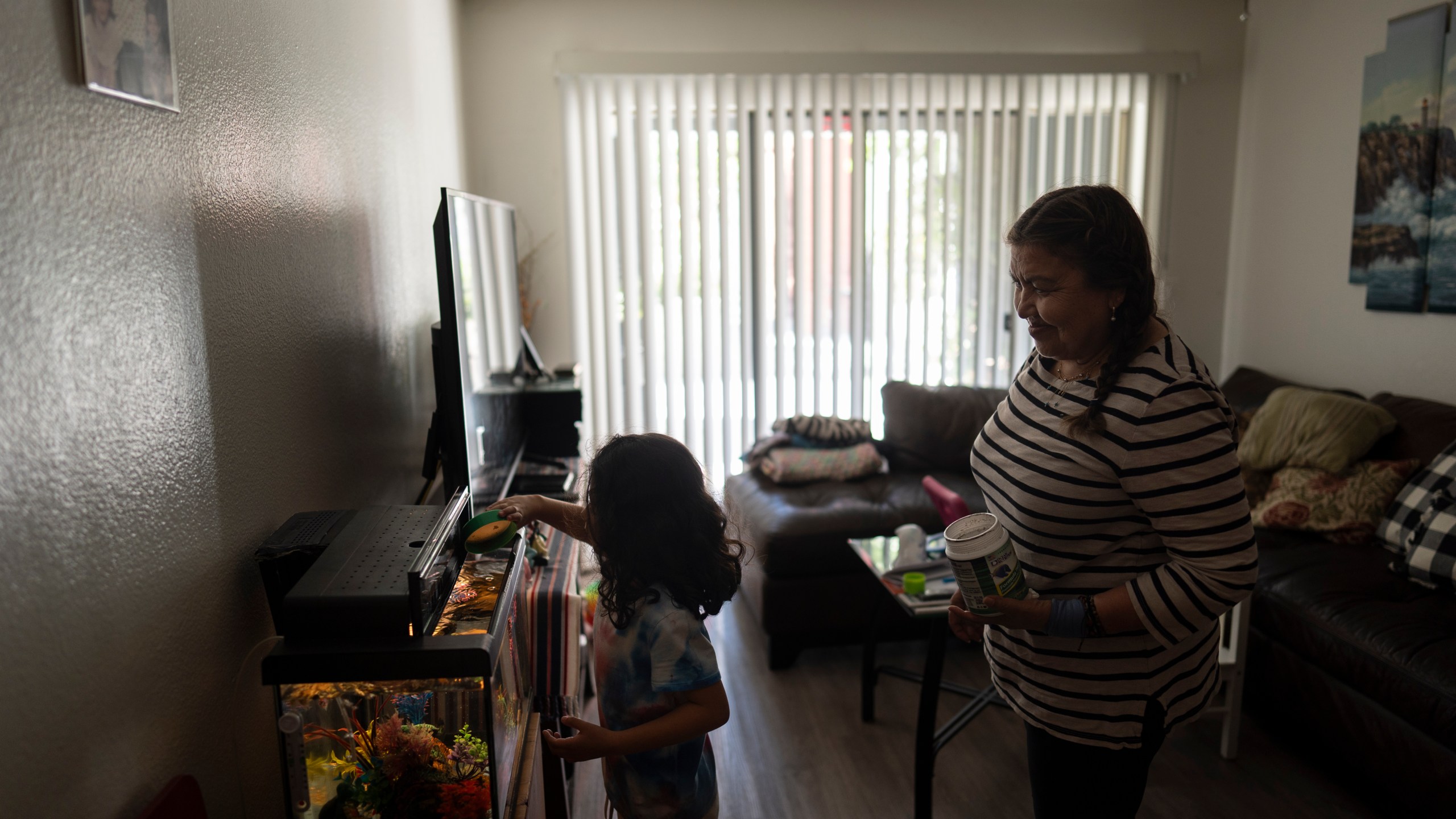 Marina Maalouf, a longtime resident of Hillside Villa, watches as her granddaughter feeds fish in their apartment in Los Angeles, Tuesday, Oct. 1, 2024. (AP Photo/Jae C. Hong)