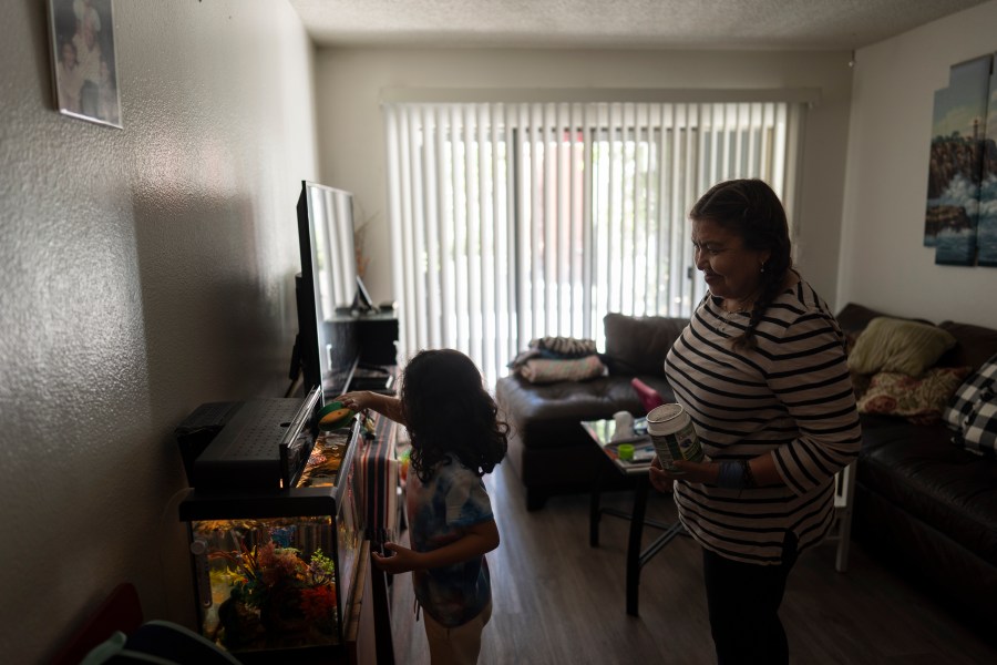 Marina Maalouf, a longtime resident of Hillside Villa, watches as her granddaughter feeds fish in their apartment in Los Angeles, Tuesday, Oct. 1, 2024. (AP Photo/Jae C. Hong)