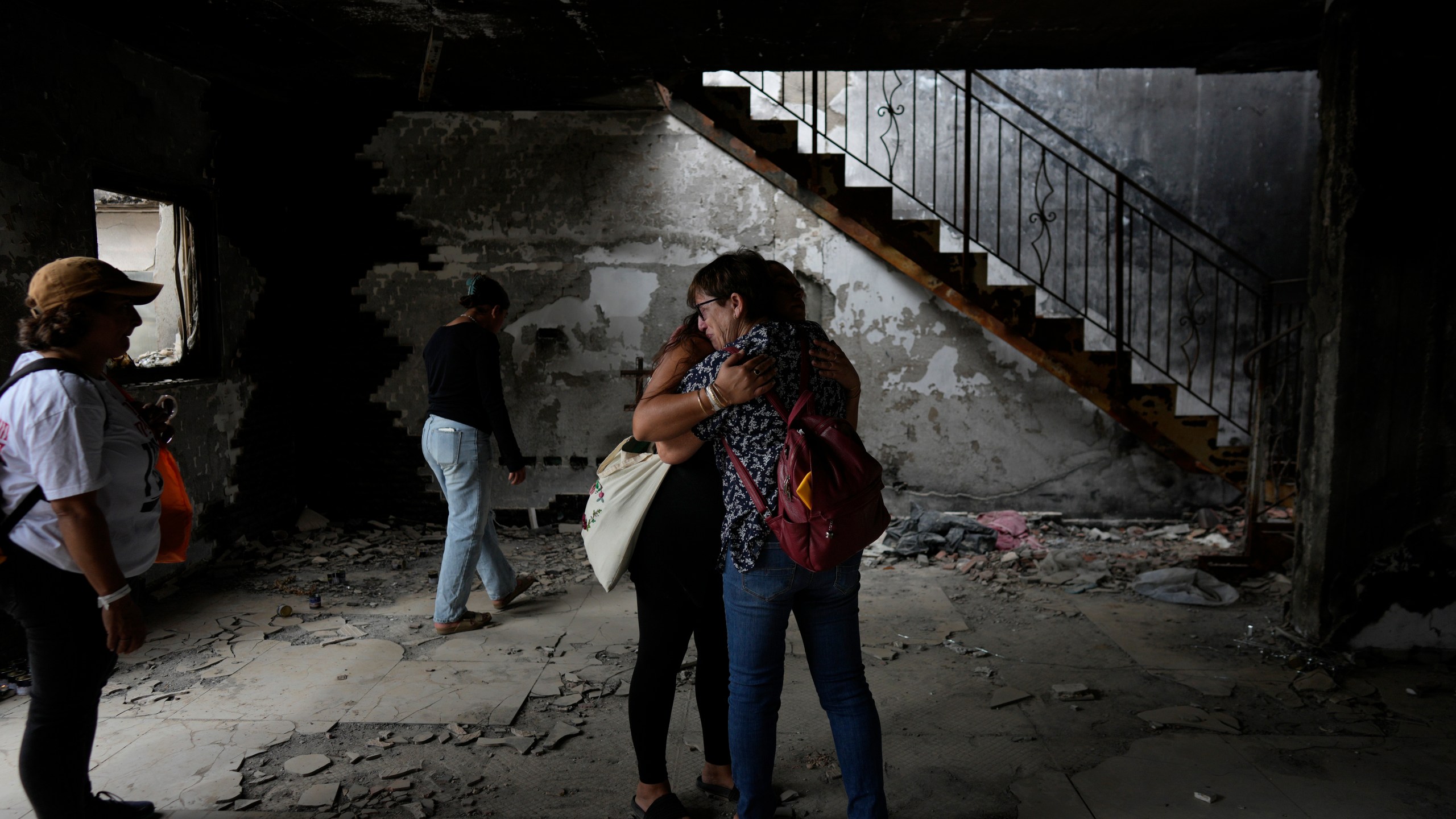 People hug at the house of Maayan and Yuval Bar killed by Hamas, as Israel marks the one-year anniversary of the Hamas attack on Israel, at the Kibbutz Be'eri, an Israeli communal farm on the Gaza border, on Monday, Oct. 7, 2024. (AP Photo/Ohad Zwigenberg)