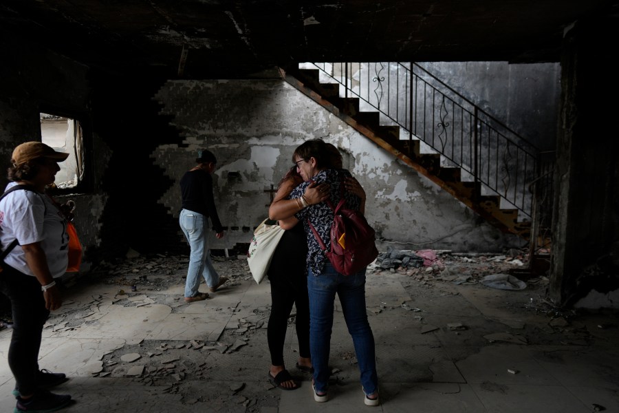 People hug at the house of Maayan and Yuval Bar killed by Hamas, as Israel marks the one-year anniversary of the Hamas attack on Israel, at the Kibbutz Be'eri, an Israeli communal farm on the Gaza border, on Monday, Oct. 7, 2024. (AP Photo/Ohad Zwigenberg)