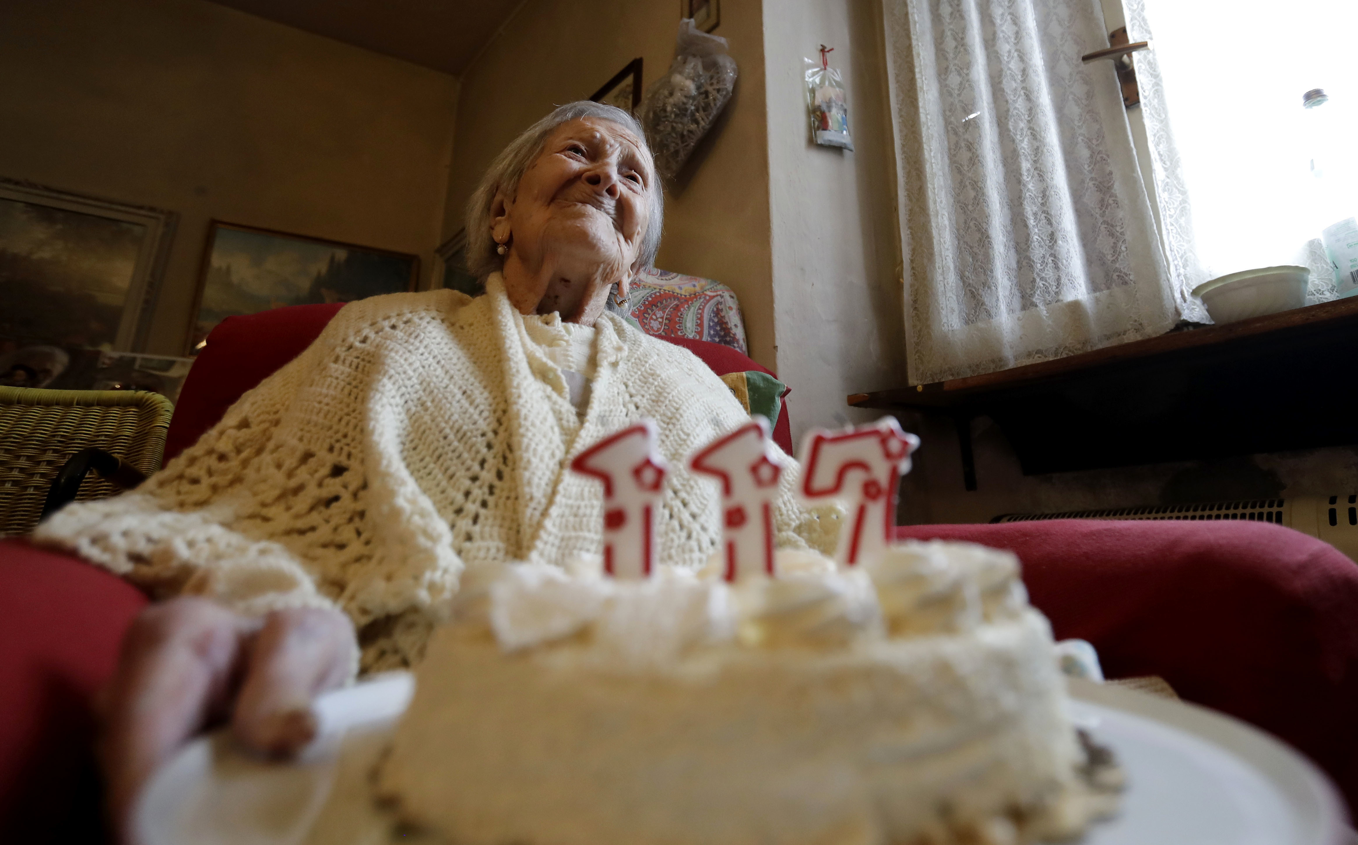 FILE- Emma Morano holds a cake with candles marking 117 years on the day of her birthday, Nov. 29, 2016, in Verbania, Italy. (AP Photo/Antonio Calanni)