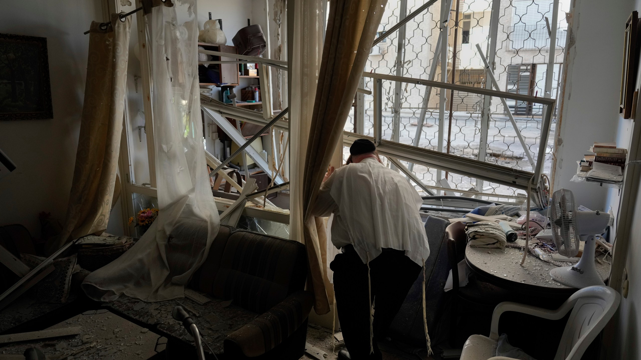 A man examine his damaged apartment that was hit by a rocket fired from Lebanon, in Kiryat Yam, northern Israel, on Tuesday, Oct. 8, 2024. (AP Photo/Ariel Schalit)