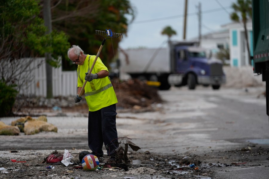 Teams work to clean up piles of debris from Hurricane Helene flooding ahead of the arrival of Hurricane Milton, in Holmes Beach on Anna Maria Island, Fla., Tuesday, Oct. 8, 2024. (AP Photo/Rebecca Blackwell)