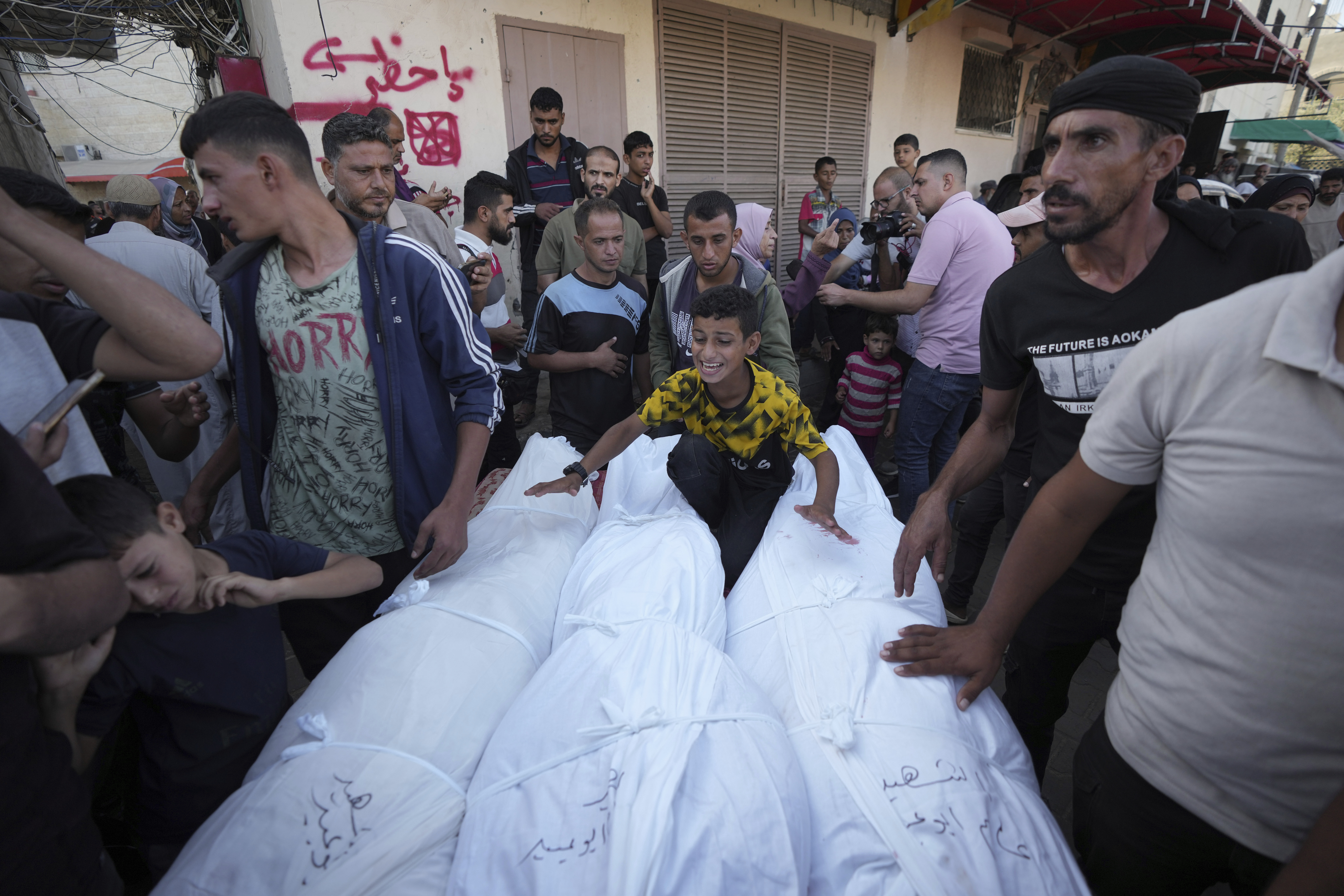 Mourners gather around bodies of Palestinians killed in the Israeli bombardment of the Gaza Strip, outside the hospital morgue in Deir al-Balah on Wednesday, Oct. 9, 2024. (AP Photo/Abdel Kareem Hana)