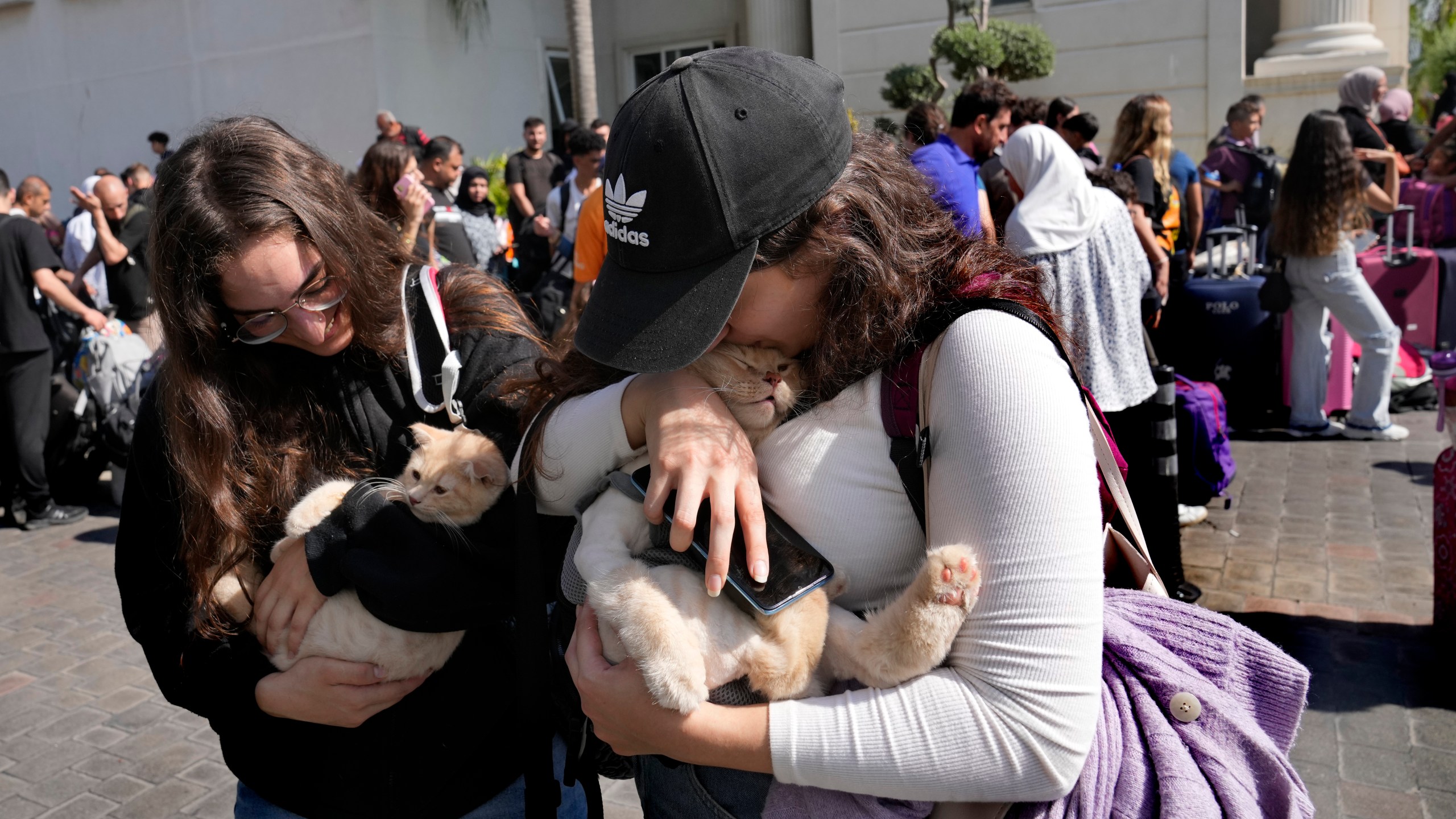 Turkish citizens carry their cats as they wait to board a Turkish navy vessel to be evacuated to Turkey at a gathering point, in Beirut, Lebanon, Wednesday, Oct. 9, 2024. (AP Photo/Hussein Malla)