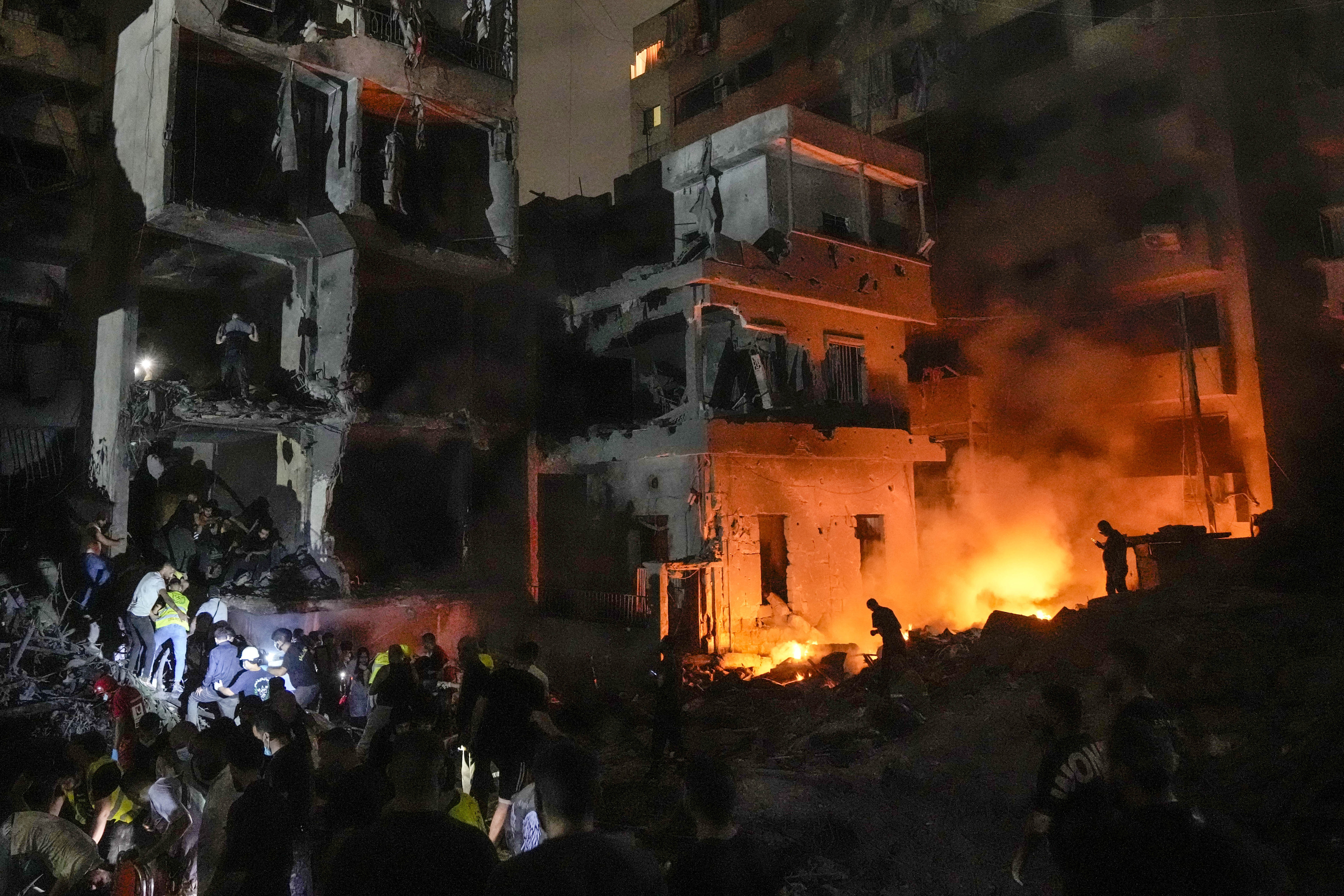 People gather in front of destroyed buildings hit by an Israeli airstrike in central Beirut, Lebanon, Thursday, Oct. 10, 2024. (AP Photo/Bilal Hussein)