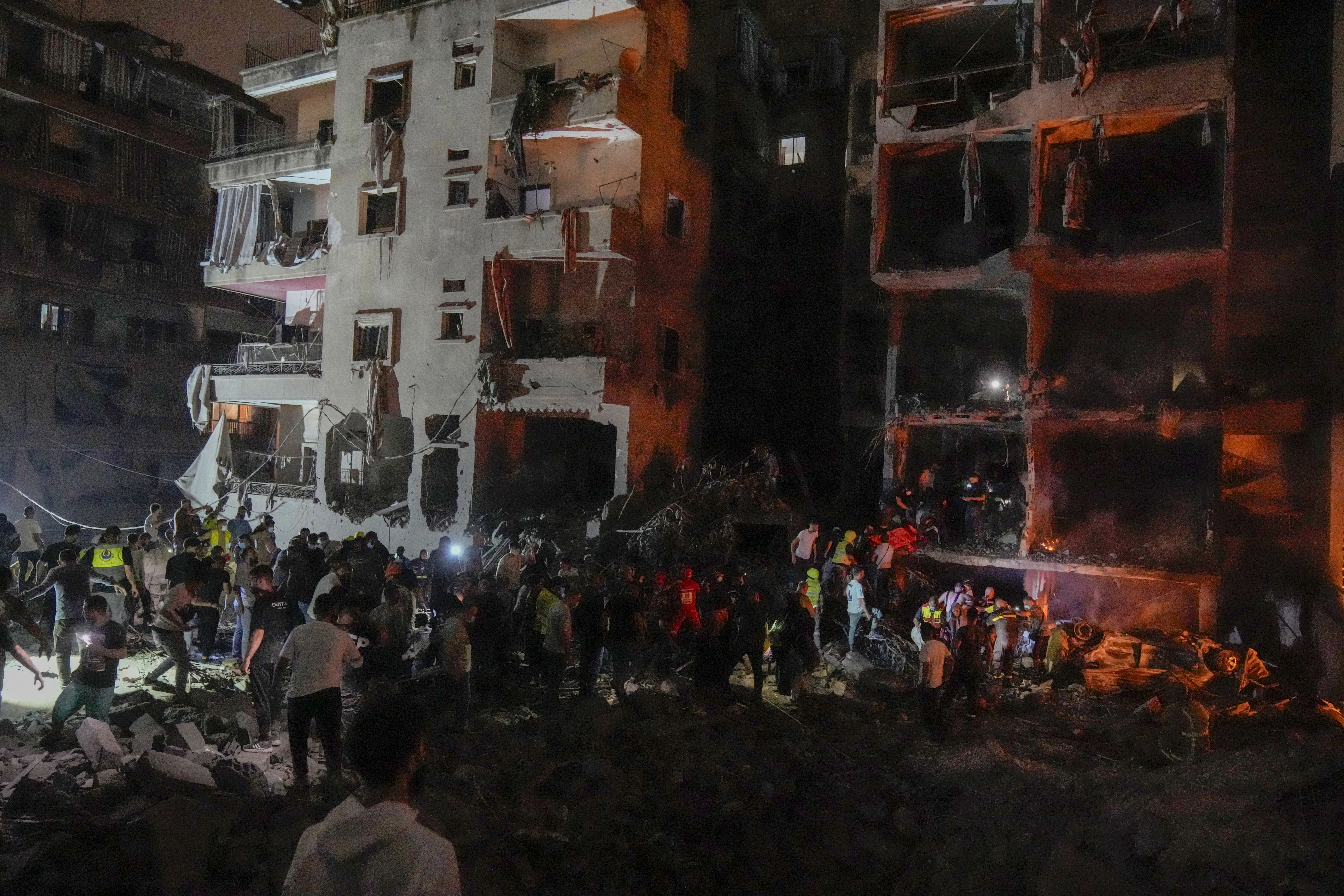 People gather in front of destroyed buildings hit by an Israeli airstrike in central Beirut, Lebanon, Thursday, Oct. 10, 2024. (AP Photo/Bilal Hussein)