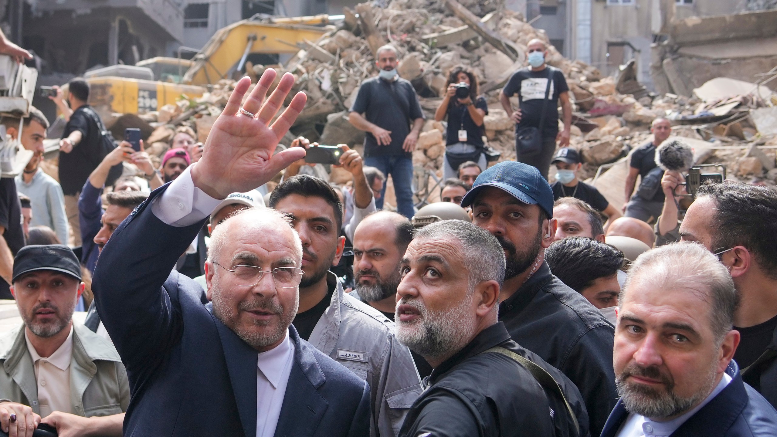 Iran's parliament speaker Mohammad Bagher Qalibaf, left, waves to residents as visit the site of Thursday's Israeli airstrike in Beirut, Lebanon, Saturday, Oct. 12, 2024. (AP Photo/Hassan Ammar)