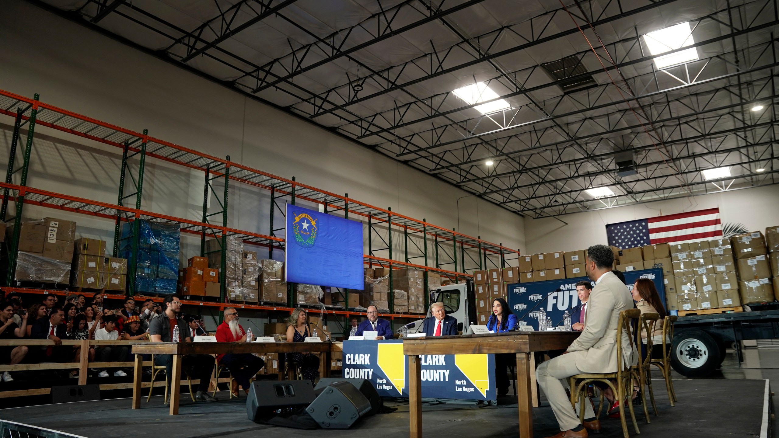 Elias Trujillo, left, listens with others at a campaign event for republican presidential nominee former President Donald Trump, center, Saturday, Oct. 12, 2024, in North Las Vegas. (AP Photo/Lucas Peltier)