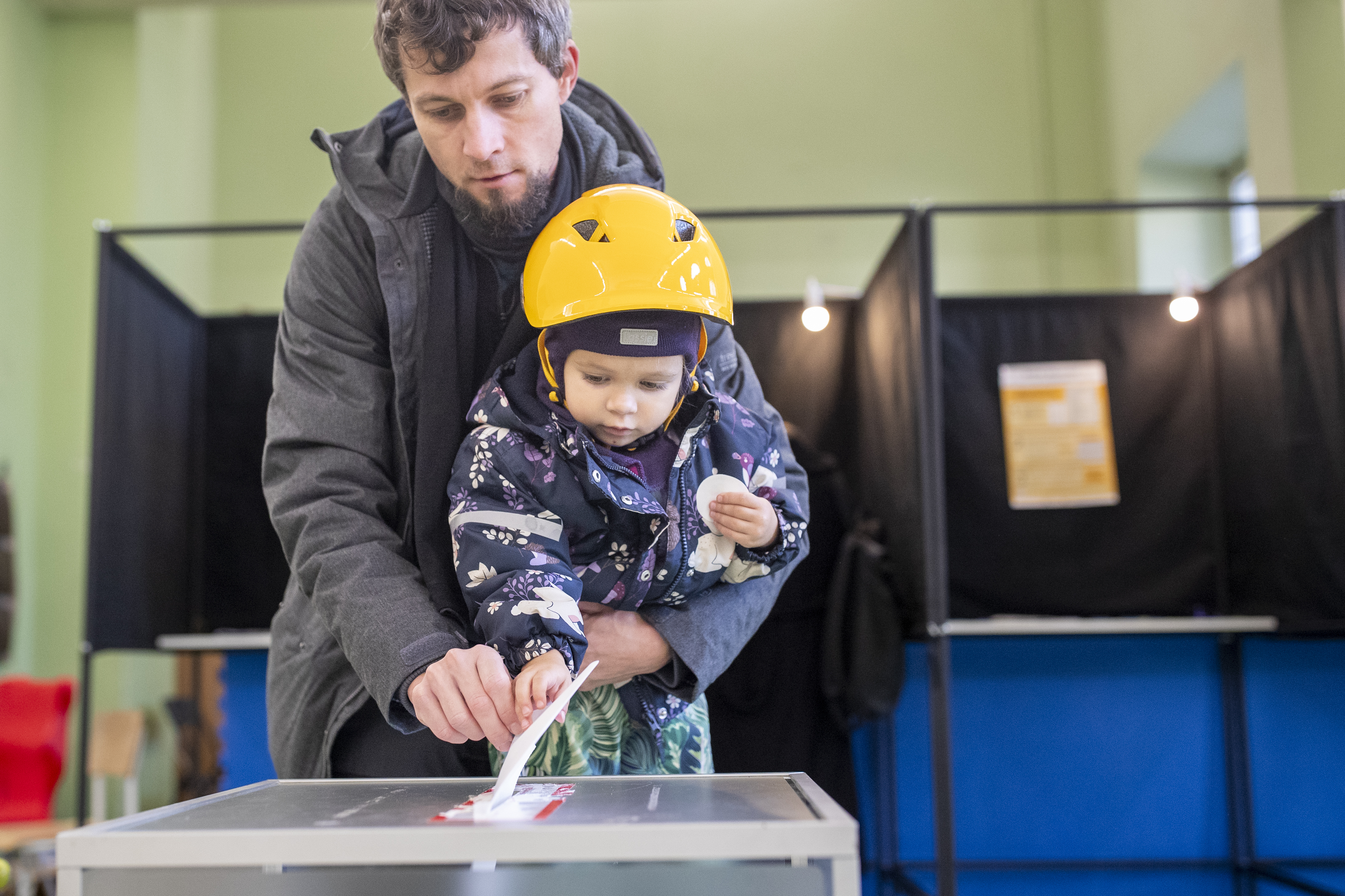 A man with a child casts his ballot at a polling station during the first round of voting in parliamentary elections, in Vilnius, Lithuania, Sunday, Oct. 13, 2024. (AP Photo/Mindaugas Kulbis)