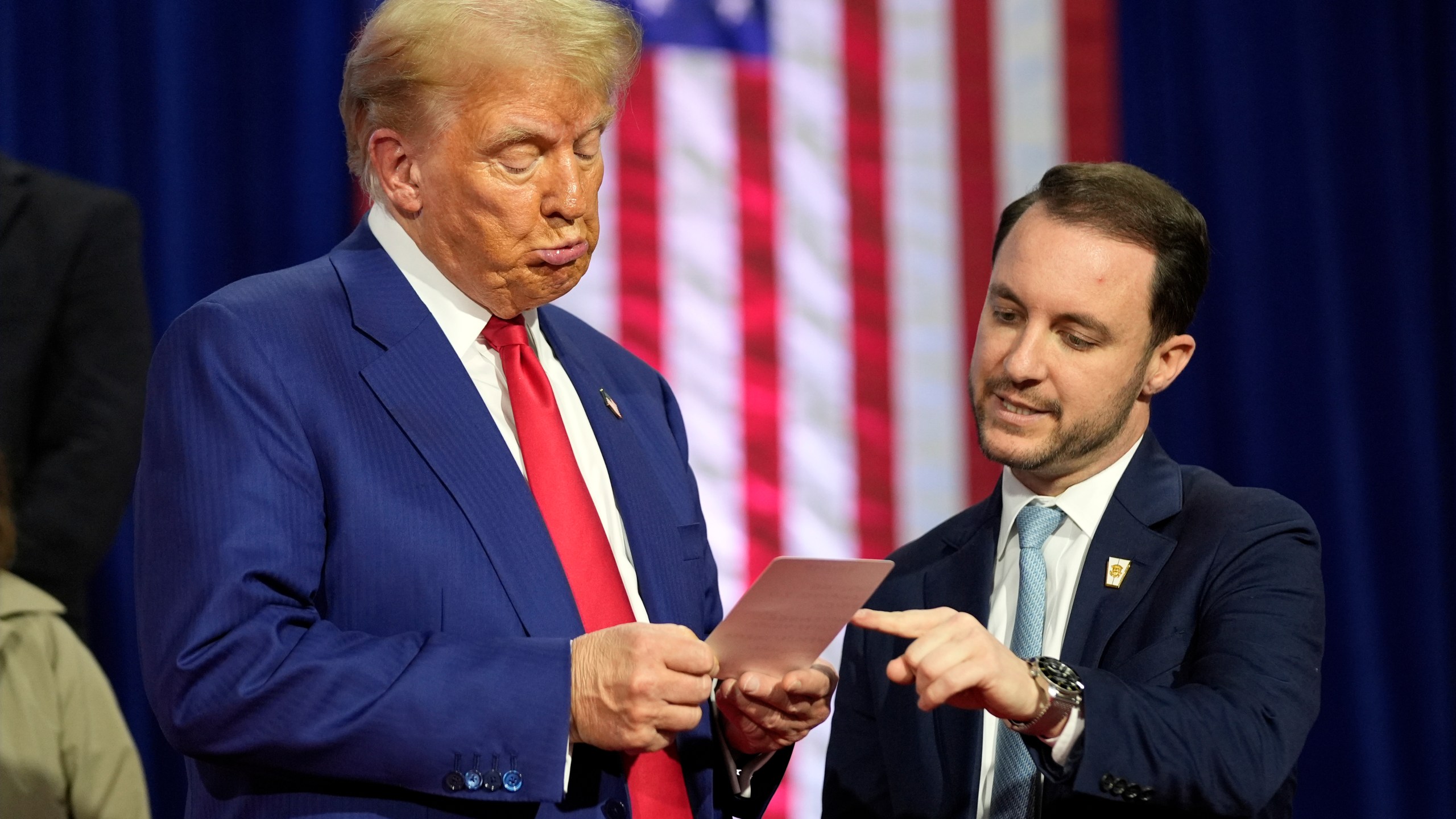 Republican presidential nominee former President Donald Trump reads a note that Justin Caporale brought onto the stage at a campaign town hall at the Greater Philadelphia Expo Center & Fairgrounds, Monday, Oct. 14, 2024, in Oaks, Pa. (AP Photo/Alex Brandon)