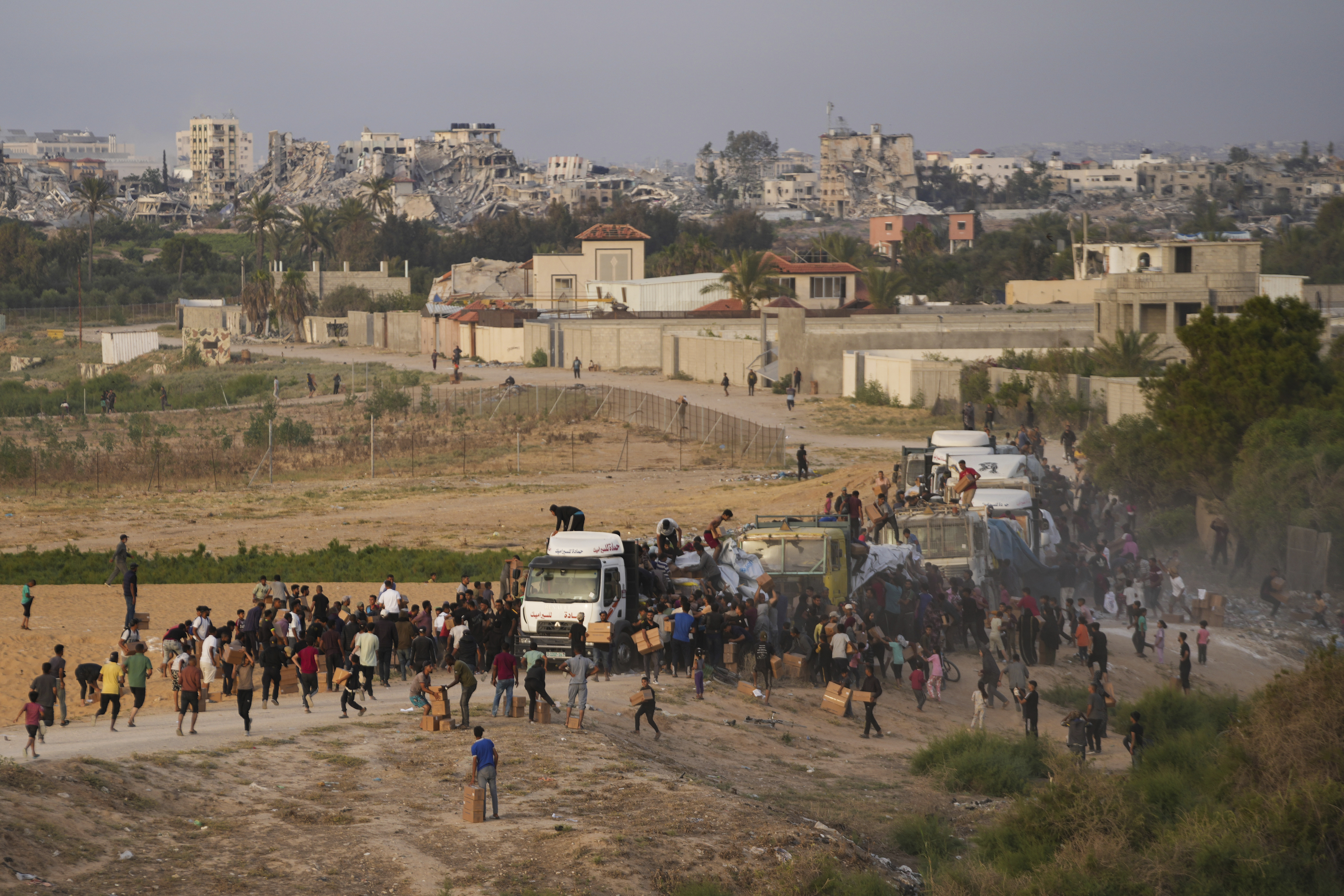 FILE - Palestinians are storming trucks loaded with humanitarian aid brought in through a new U.S.-built pier, in the central Gaza Strip, May 18, 2024. (AP Photo/Abdel Kareem Hana, File)