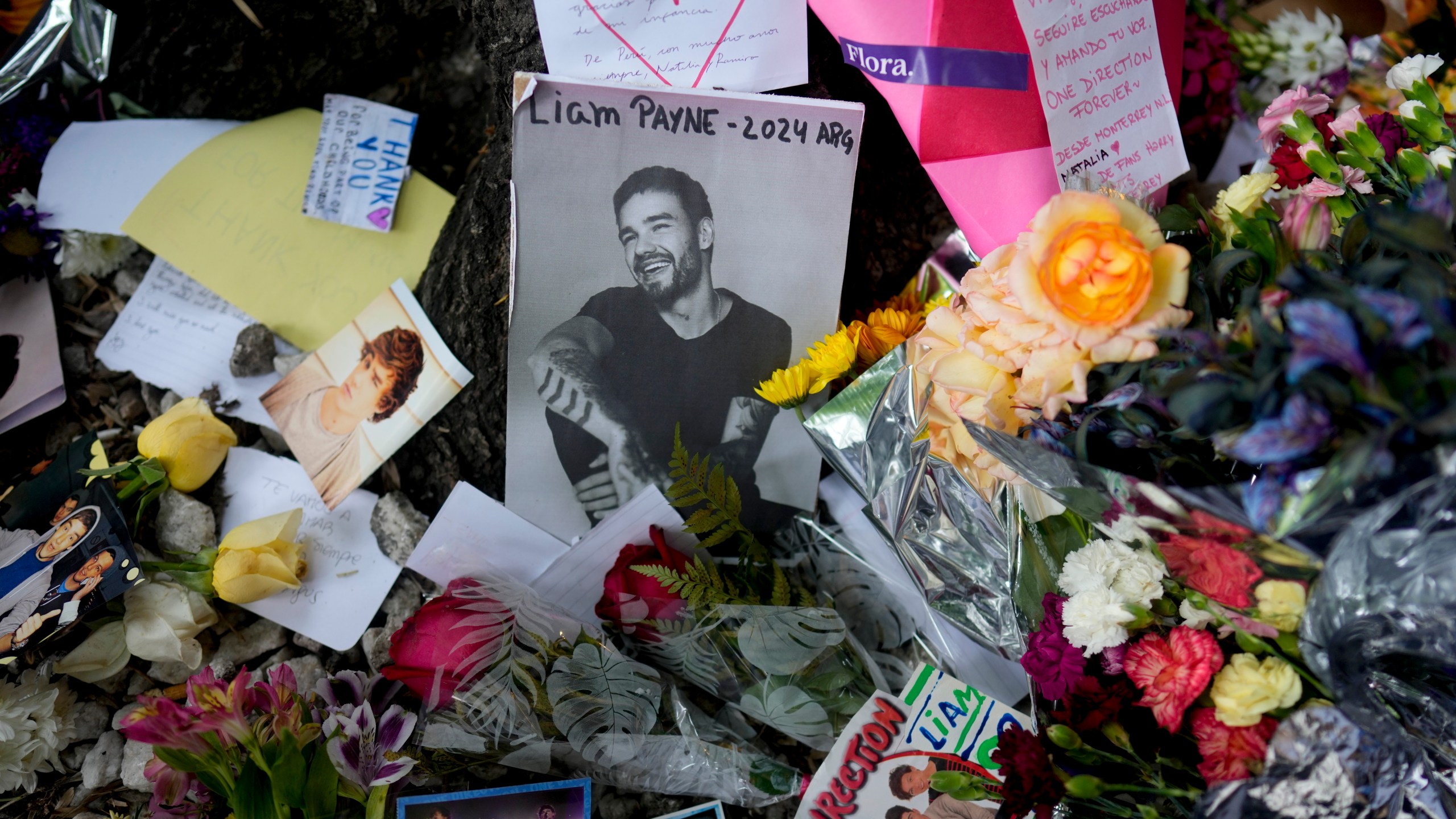 A picture of former One Direction singer Liam Payne sits surrounded by flowers and candles as fans gather outside the hotel where he was found dead after falling from a balcony in Buenos Aires, Argentina, Thursday, Oct. 17, 2024. (AP Photo/Natacha Pisarenko)