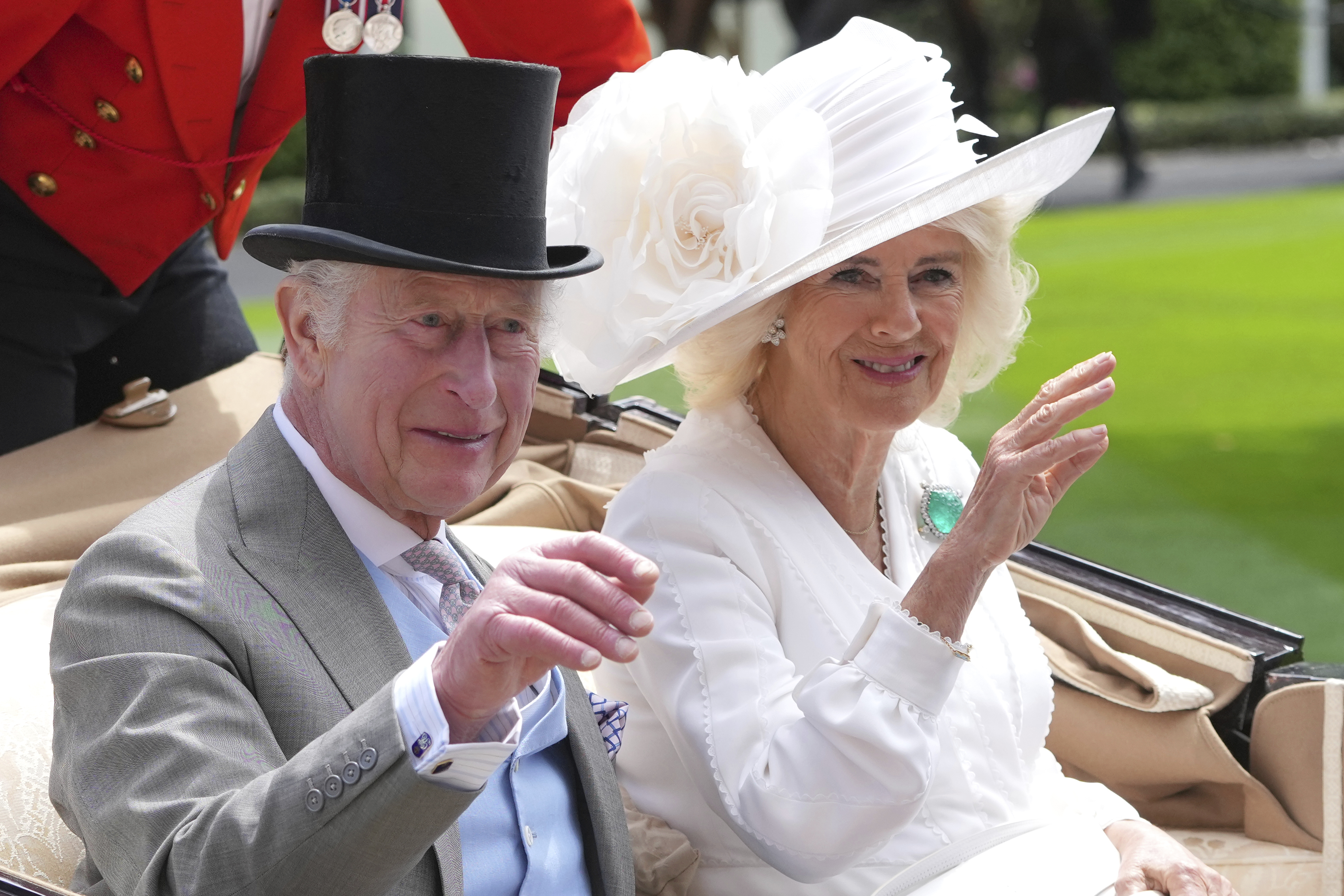 FILE - Britain's King Charles III and Queen Camilla wave to the crowds as they arrive by carriage in the parade ring on the third day of the Royal Ascot, horse race meeting, traditional known as Ladies Day, at Ascot, England, on June 20, 2024. (AP Photo/Kin Cheung, File)