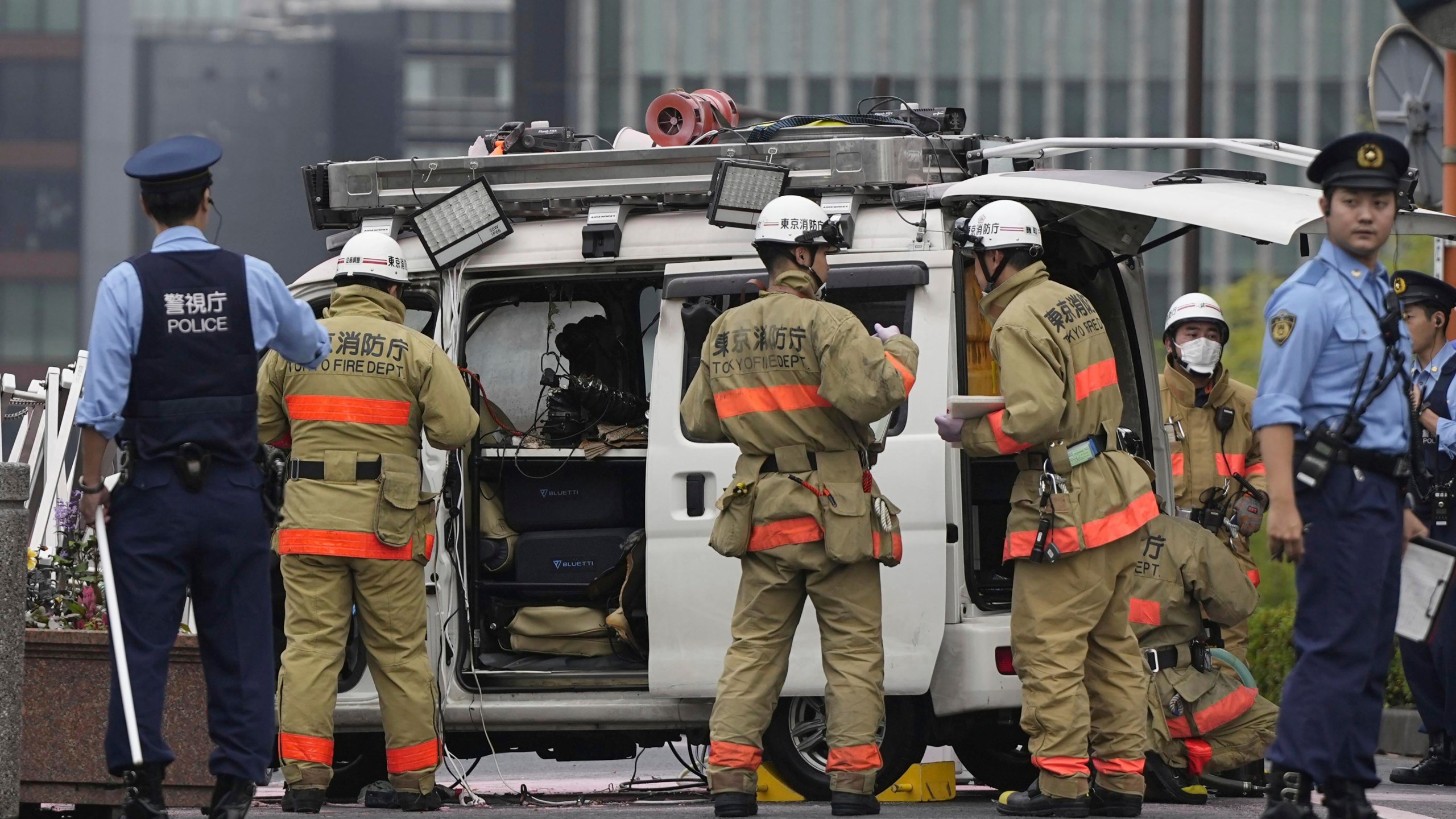 Officials work near a vehicle which was stuck against a security fence near the prime minister's office in Tokyo Saturday, Oct. 19, 2024. (Kyodo News via AP)