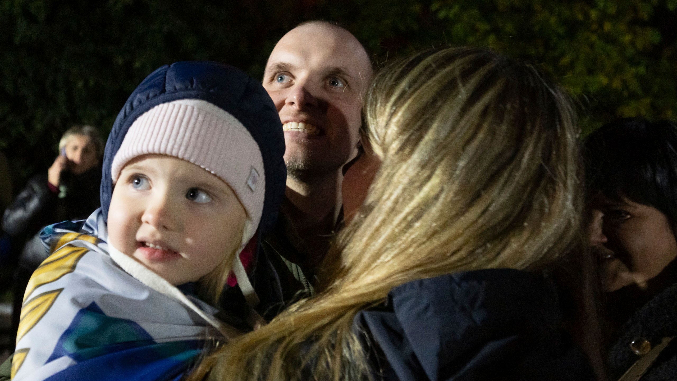 In this photo provided by the Press Service of the President of Ukraine on Oct. 19, 2024, a Ukrainian serviceman hugs his family after returning from captivity during a POWs exchange in an undisclosed location, Ukraine. (Press Service of the President of Ukraine via AP)