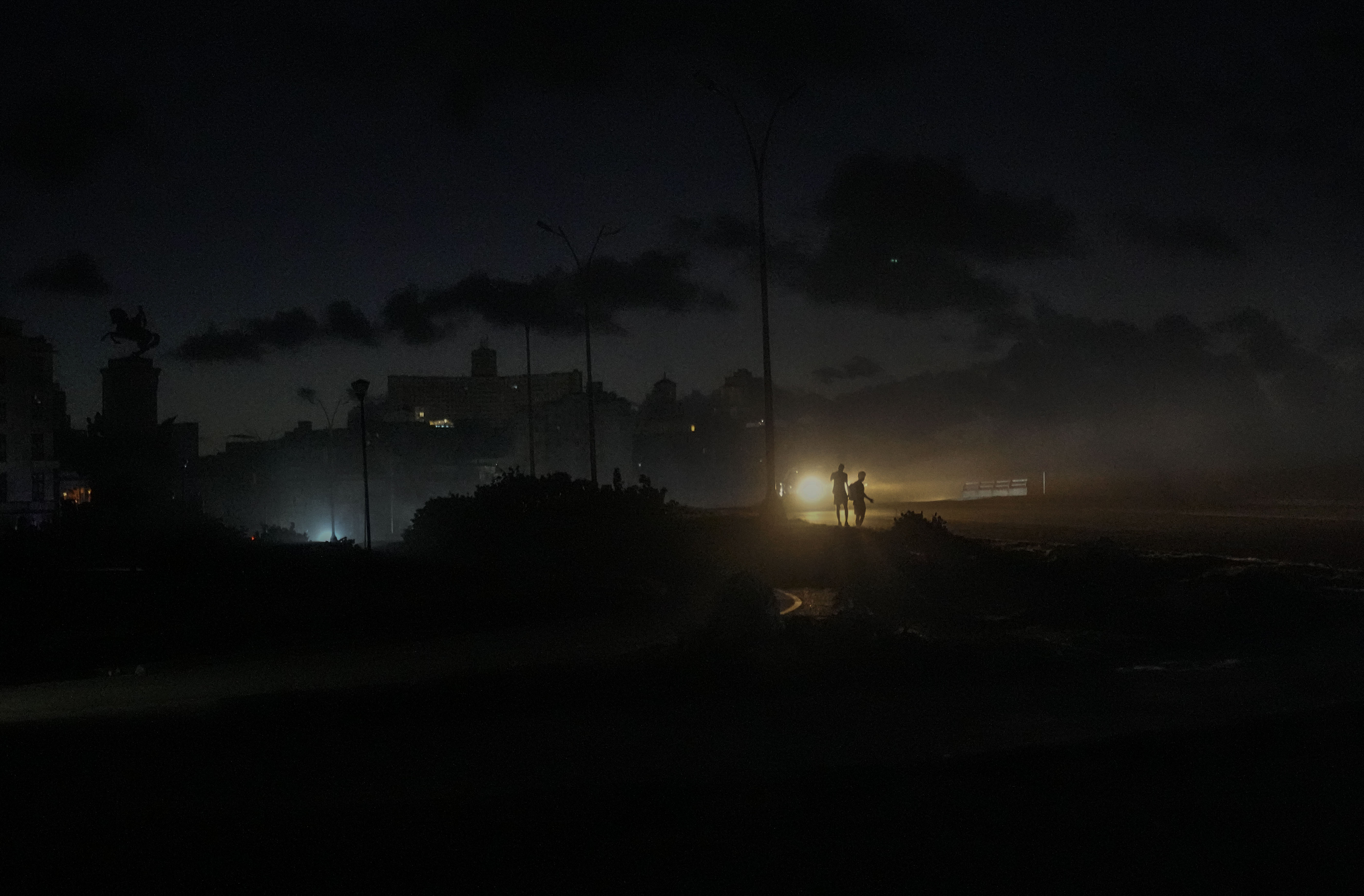 Residents walk on a street during a blackout following the failure of a major power plant in Havana, Cuba, Sunday, Oct. 20, 2024. (AP Photo/Ramon Espinosa)