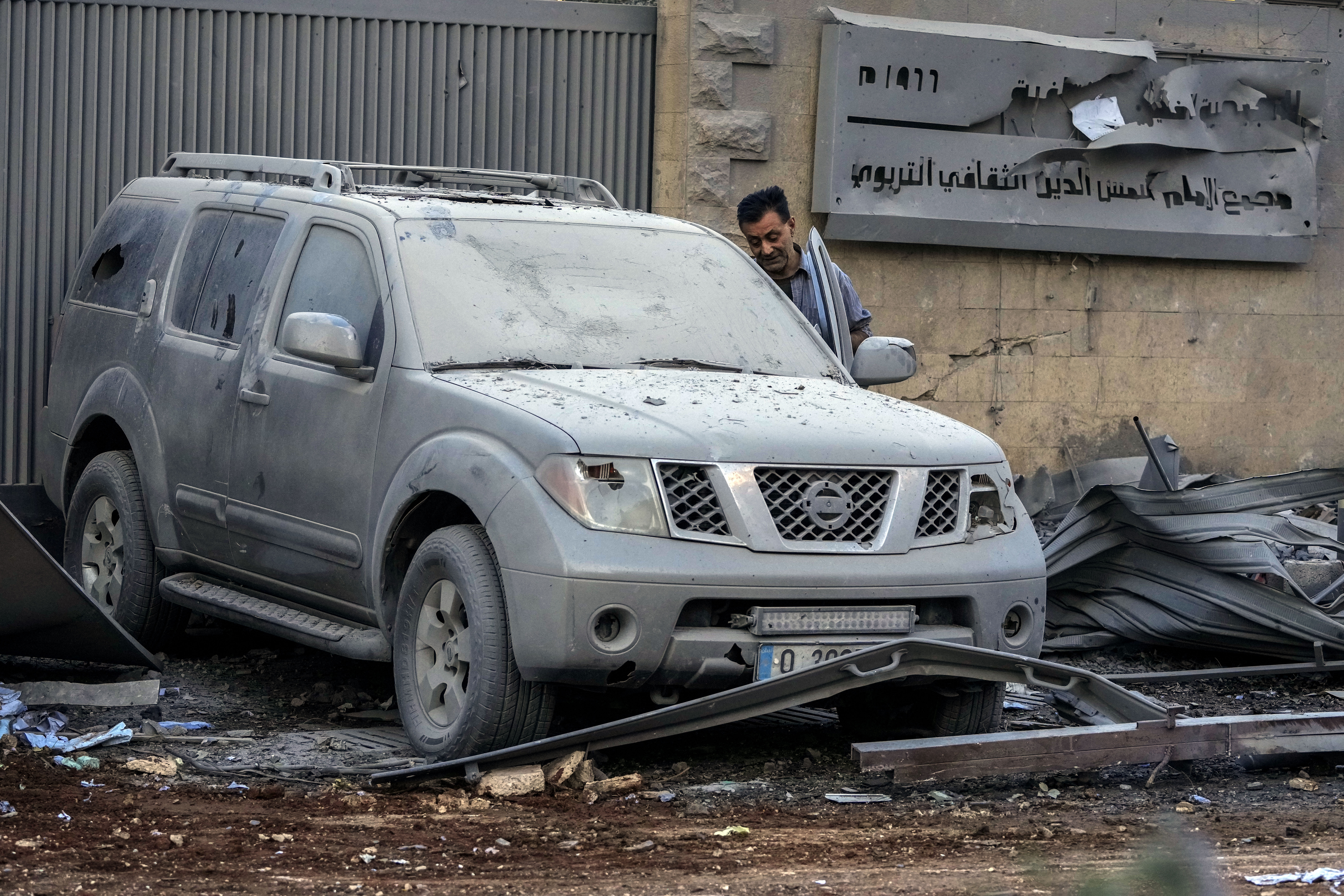 A man checks his destroyed car at the site of an Israeli airstrike that hit several branches of the Hezbollah-run al-Qard al-Hassan in Dahiyeh, Beirut, Lebanon, Monday, Oct. 21, 2024. (AP Photo/Hassan Ammar)