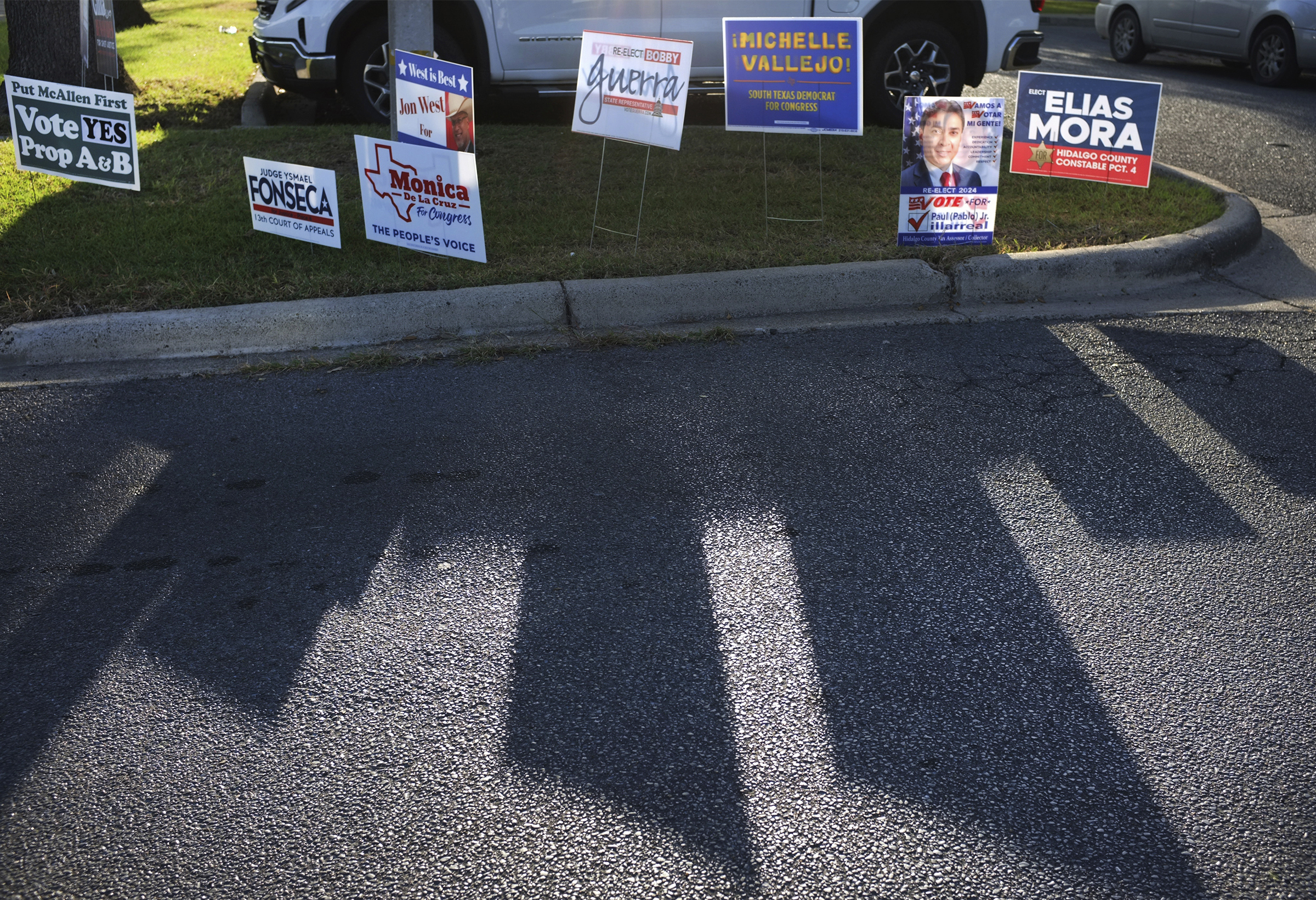 FILE - Campaign signs for candidates cast a shadow on the street during early voting at Lark Library, Oct. 21, 2024, in McAllen, Texas. (Delcia Lopez/The Monitor via AP, File)