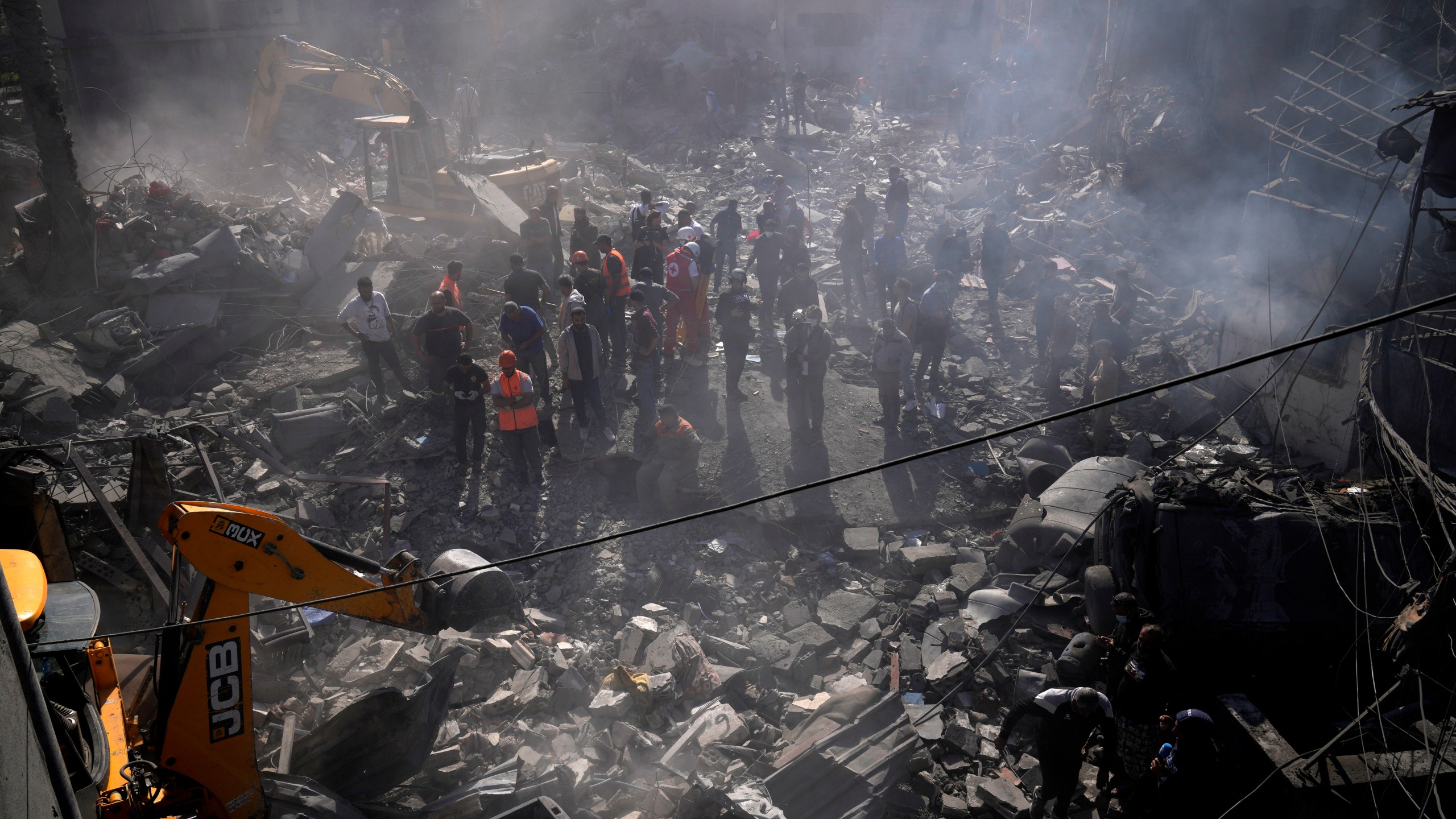 An excavator sifts through the rubble as rescue workers search for victims at the site of Israeli airstrikes that destroyed buildings, facing the city's main government hospital in a densely-populated neighborhood, in southern Beirut, Lebanon, Tuesday, Oct. 22, 2024. (AP Photo/Hussein Malla)