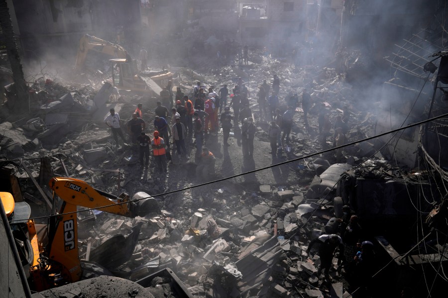 An excavator sifts through the rubble as rescue workers search for victims at the site of Israeli airstrikes that destroyed buildings, facing the city's main government hospital in a densely-populated neighborhood, in southern Beirut, Lebanon, Tuesday, Oct. 22, 2024. (AP Photo/Hussein Malla)