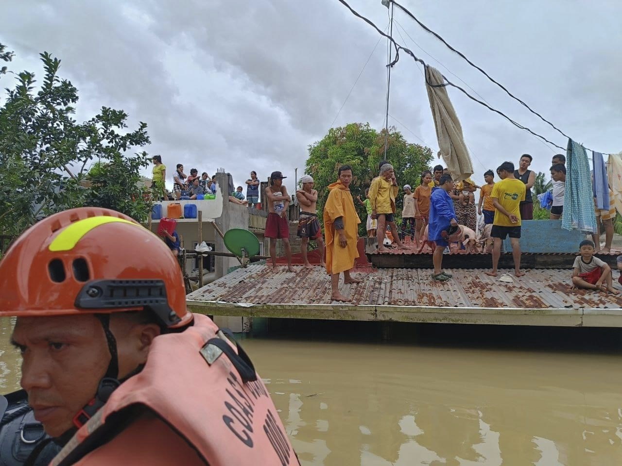 In this photo provided by the Philippine Coast Guard, residents wait on top of their roofs to avoid floods caused by Tropical Storm Trami in Libon, Albay province, Philippines on Wednesday Oct. 23, 2024. (Philippine Coast Guard via AP)