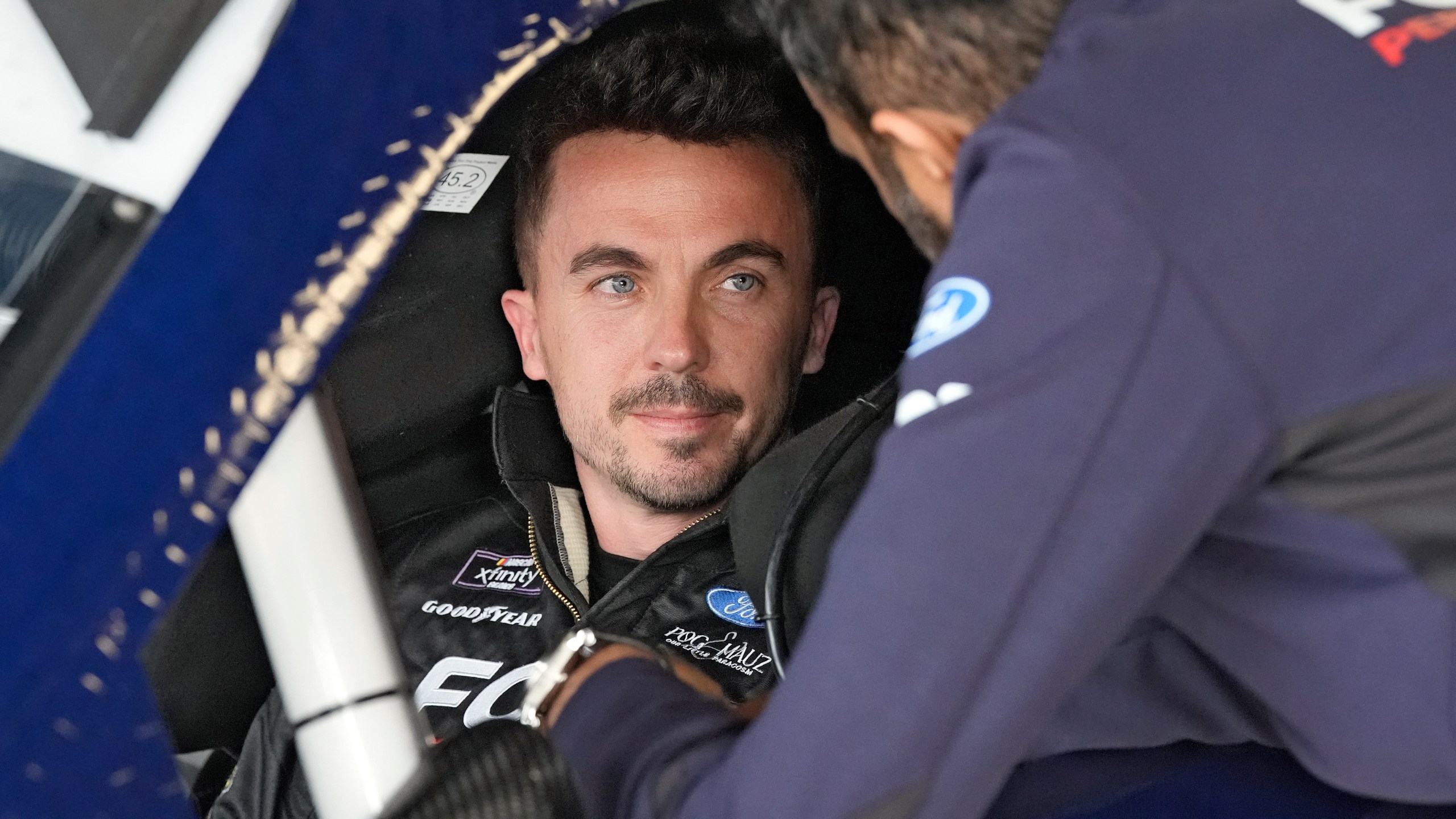 FILE - Race car driver and actor Frankie Muniz, left, talks to a crew member before a practice run, Feb. 16, 2024, at Daytona International Speedway in Daytona Beach, Fla. (AP Photo/Chris O'Meara, File)