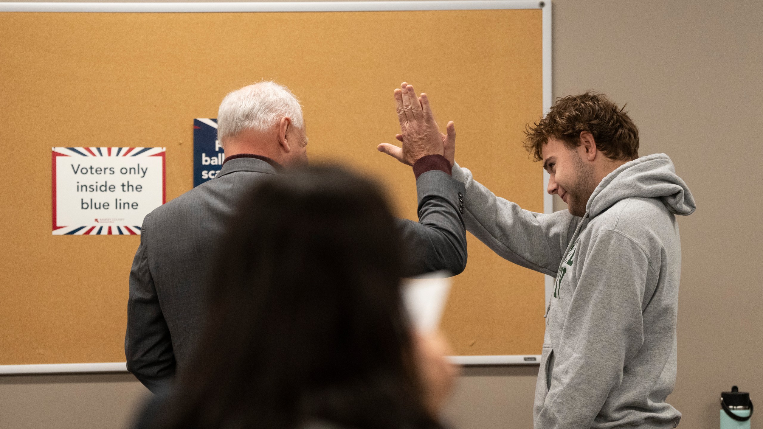 Democratic vice presidential nominee Minnesota Gov. Tim Walz, left, high-fives his son, Gus Walz, a first-time voter, as they cast their ballots during early voting at the Ramsey County Elections office in St. Paul, Minn., Wednesday, Oct. 23, 2024. (Renée Jones Schneider/Star Tribune via AP, Pool)