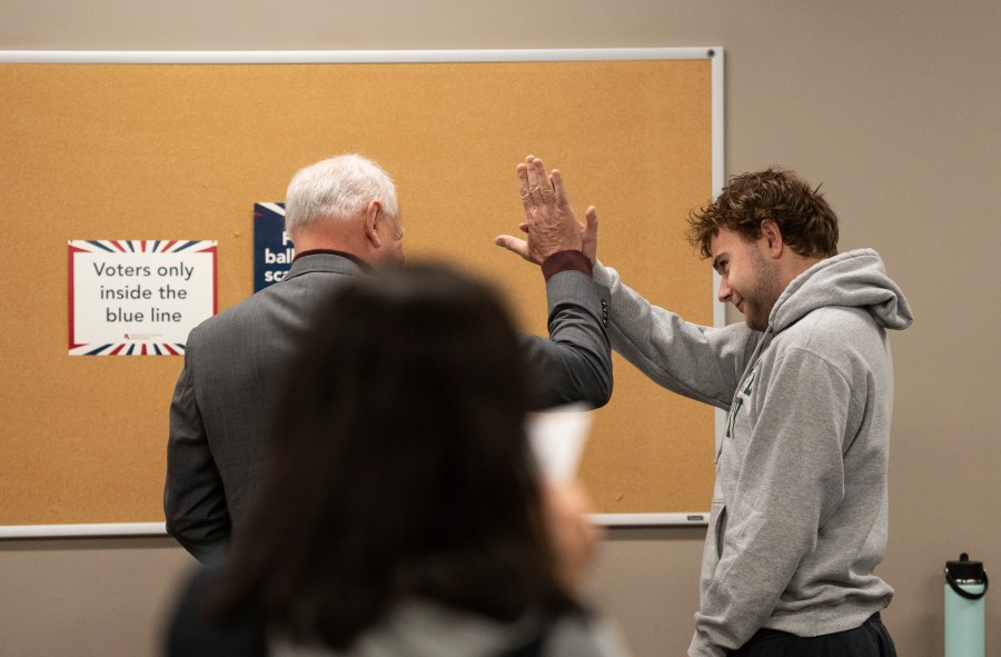 Democratic vice presidential nominee Minnesota Gov. Tim Walz, left, high-fives his son, Gus Walz, a first-time voter, as they cast their ballots during early voting at the Ramsey County Elections office in St. Paul, Minn., Wednesday, Oct. 23, 2024. (Renée Jones Schneider/Star Tribune via AP, Pool)