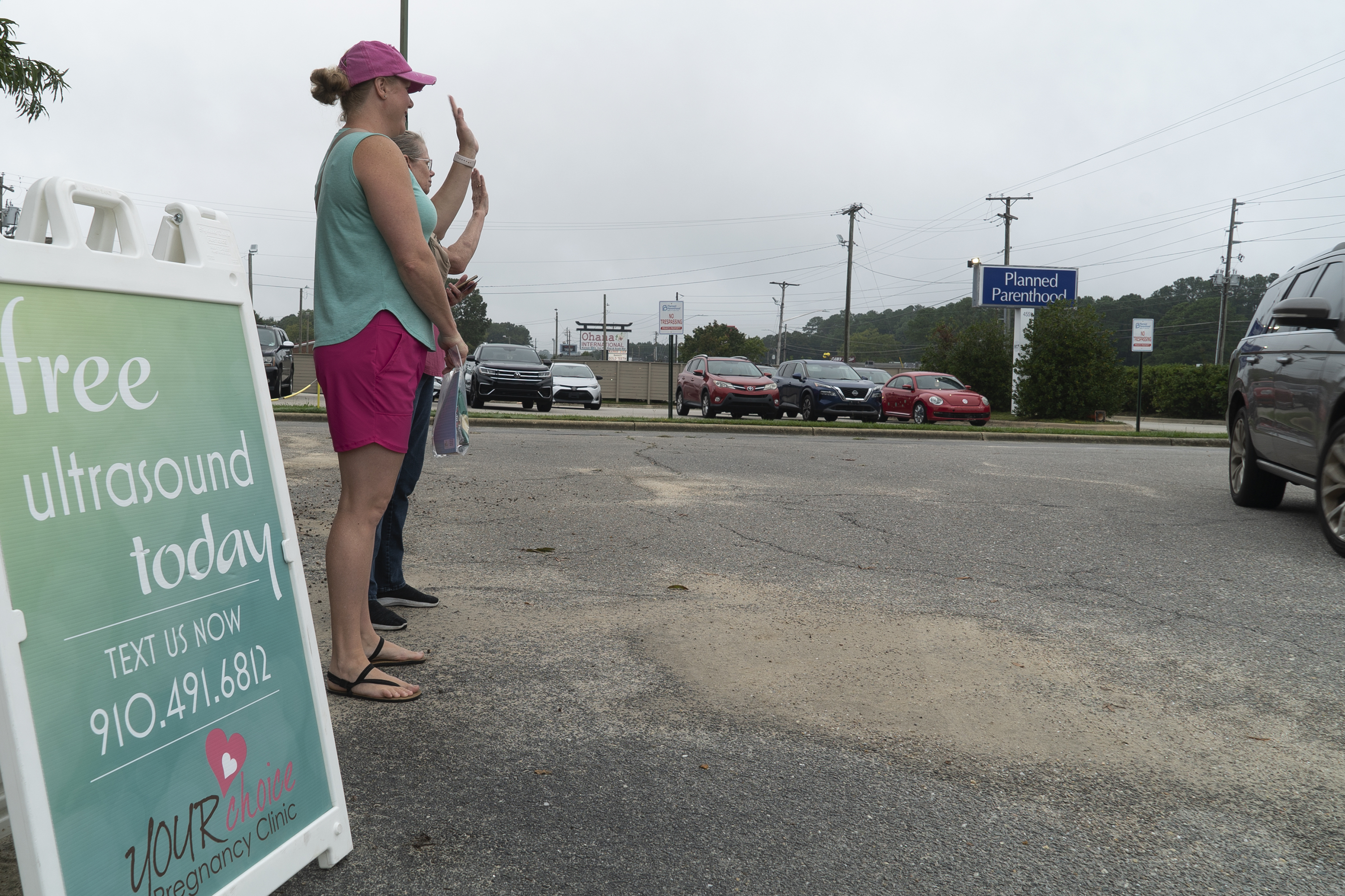 Air Force veteran and mother of two Laura Browne waves to a passing vehicle outside a Planned Parenthood clinic in Fayetteville, N.C., on Tuesday, Oct. 1, 2024. Browne does sidewalk ministry for a pregnancy center just up the road. (AP Photo/Allen G. Breed)