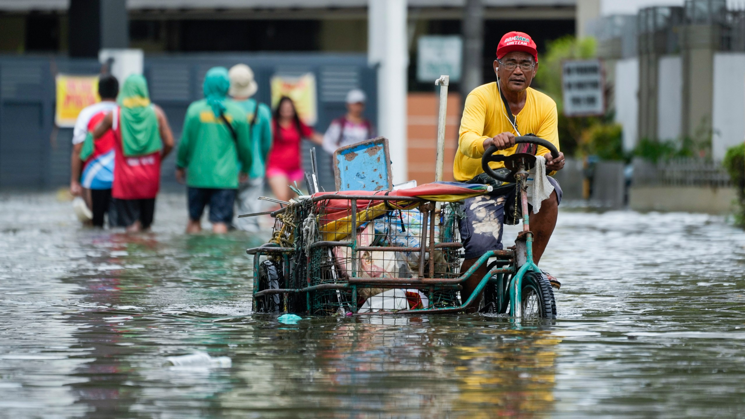 A man navigates flooded streets caused by Tropical Storm Trami on Friday, Oct. 25, 2024, in Cainta, Rizal province, Philippines. (AP Photo/Aaron Favila)