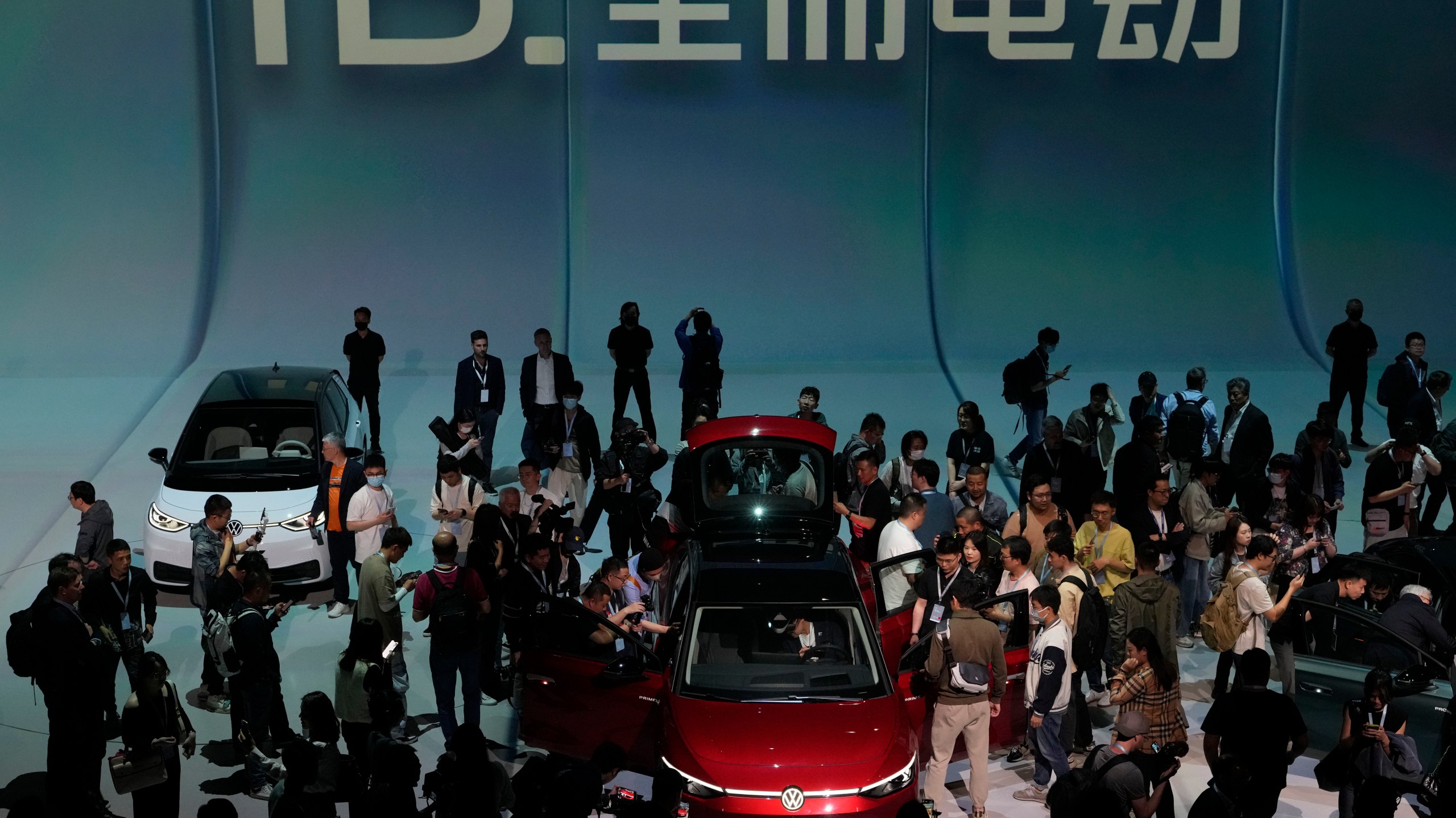 FILE - Attendees take a close look at the Volkswagen ID.7 Vizzion, a new electric flagship sedan during a world premiere on the eve of the Auto Shanghai 2023 show in Shanghai, China, April 17, 2023. (AP Photo/Ng Han Guan, File)