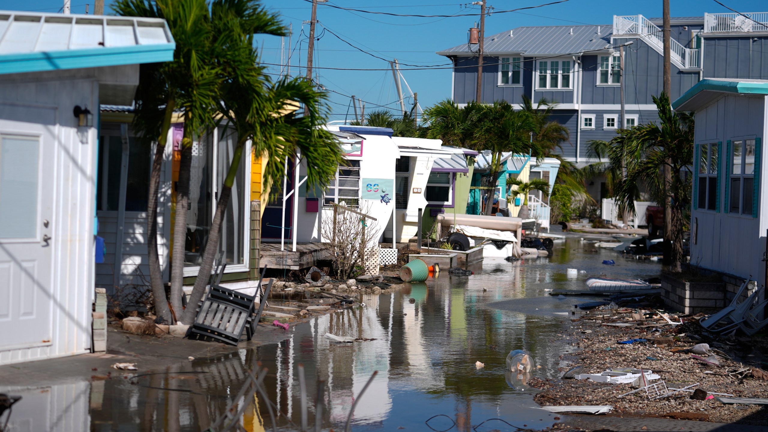 Water left by Hurricane Milton floods a road inside Pines Trailer Park, where debris was still piled outside homes from Hurricane Helene, in Bradenton Beach on Anna Maria Island, Fla., Thursday, Oct. 10, 2024. (AP Photo/Rebecca Blackwell)