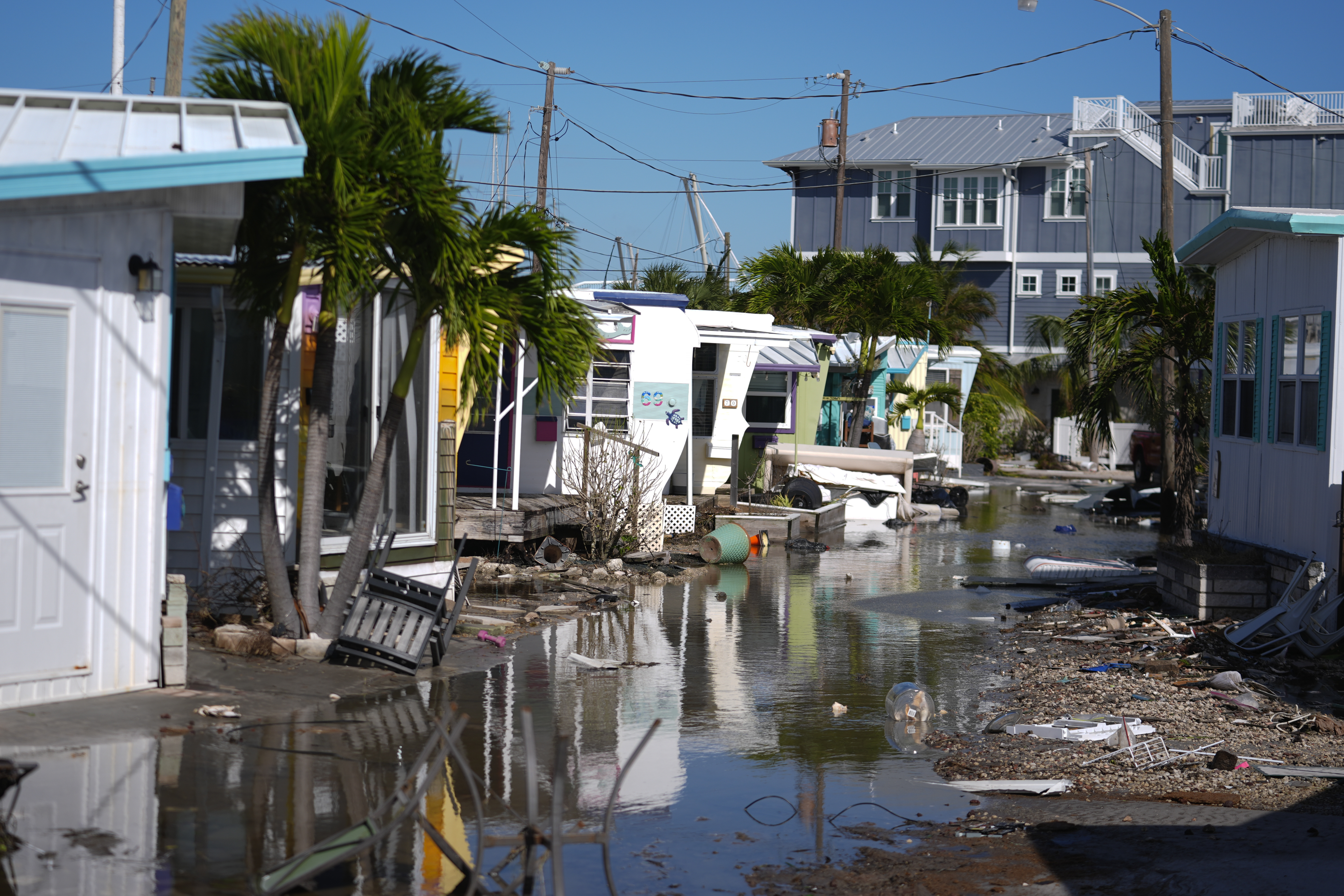 Water left by Hurricane Milton floods a road inside Pines Trailer Park, where debris was still piled outside homes from Hurricane Helene, in Bradenton Beach on Anna Maria Island, Fla., Thursday, Oct. 10, 2024. (AP Photo/Rebecca Blackwell)