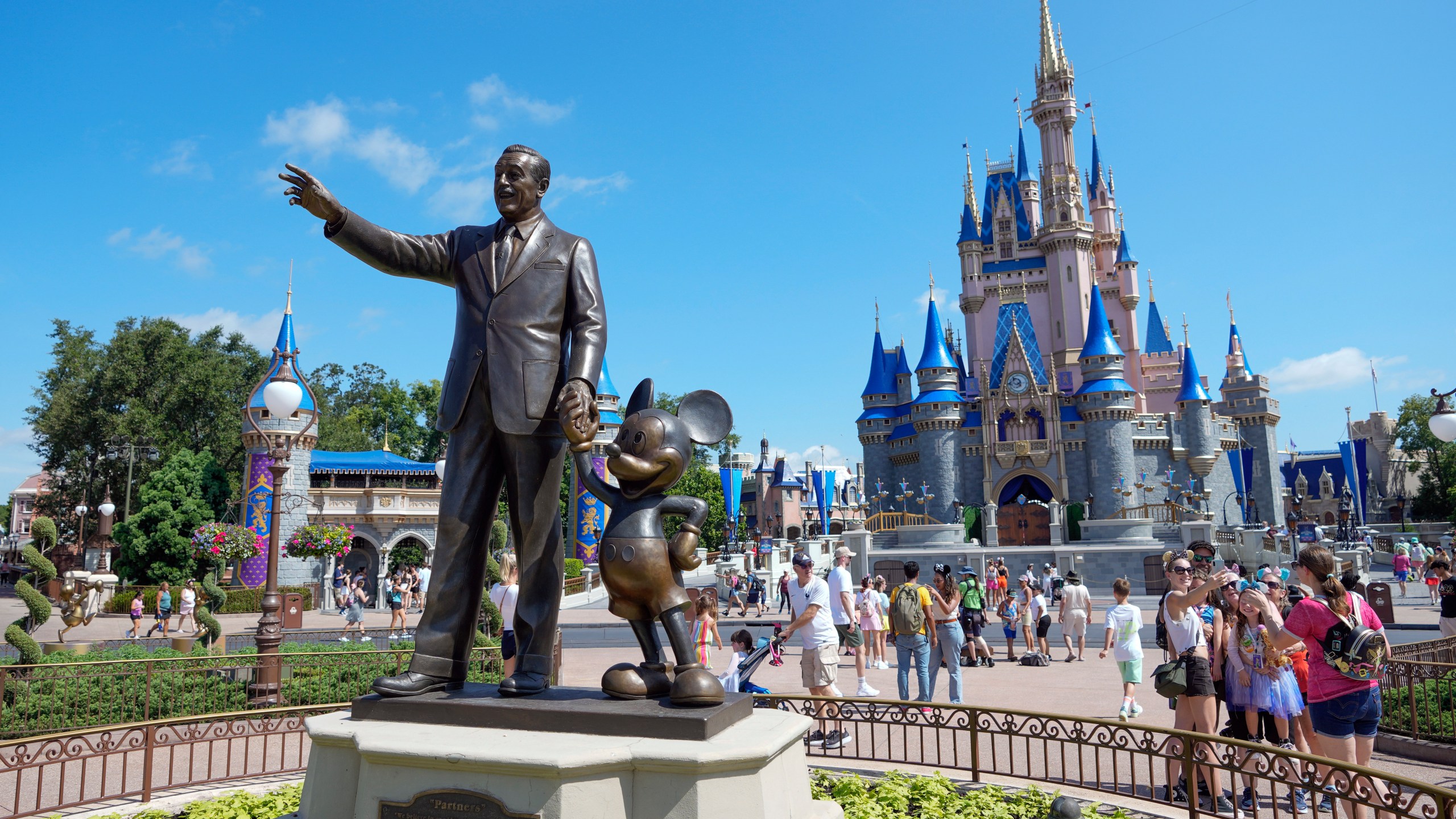 FILE - Guests pass a statue of Walt Disney and Mickey Mouse in the Magic Kingdom at Walt Disney World on July 14, 2023, in Lake Buena Vista, Fla. (AP Photo/John Raoux, File)