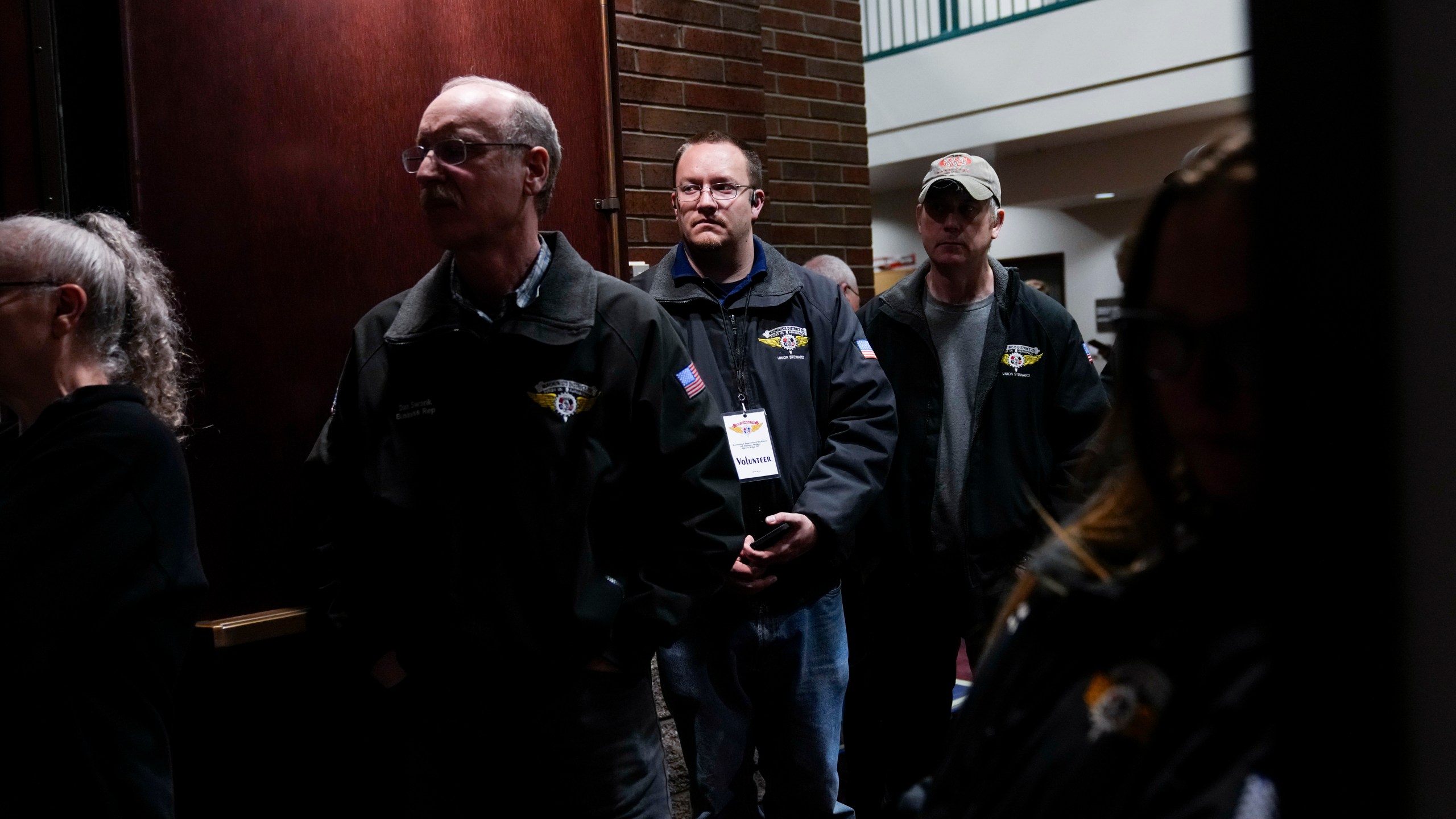 Workers listen as IAM District 751 president Jon Holden gives a press conference after announcing the union voted to accept a new contract offer from Boeing, Monday, Nov. 4, 2024, at their union hall in Seattle. (AP Photo/Lindsey Wasson)