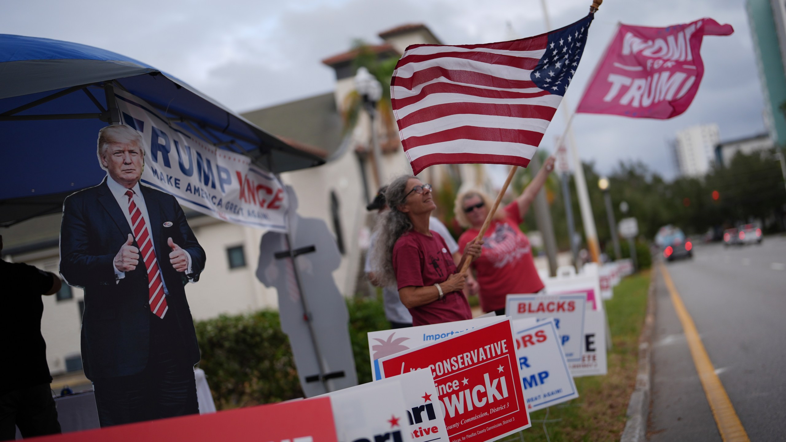 Supporters of Republican presidential nominee former President Donald Trump wave flags outside a polling place at the Coliseum in downtown St. Petersburg, Fla., on Election Day, Tuesday, Nov. 5, 2024. (AP Photo/Rebecca Blackwell)