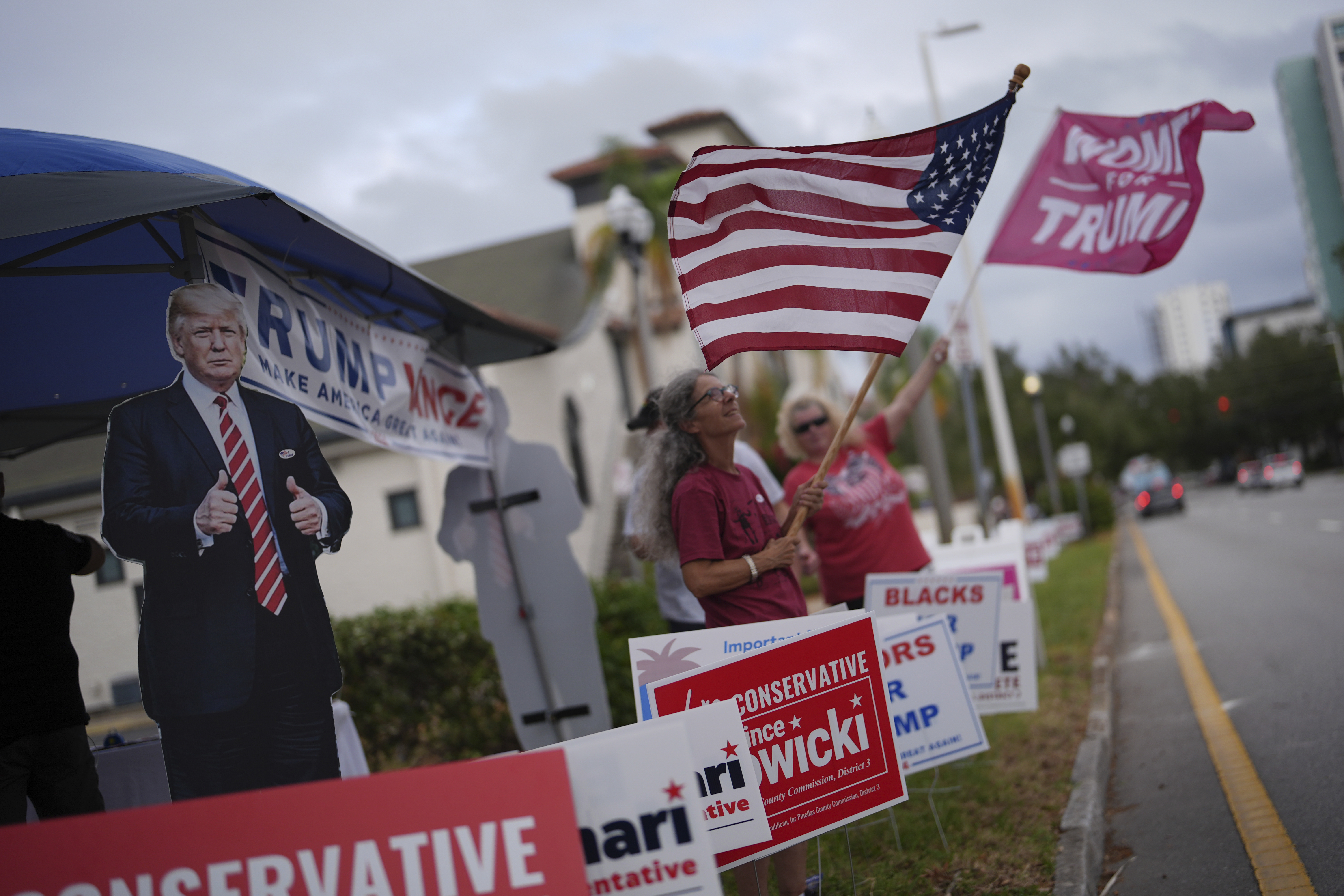 Supporters of Republican presidential nominee former President Donald Trump wave flags outside a polling place at the Coliseum in downtown St. Petersburg, Fla., on Election Day, Tuesday, Nov. 5, 2024. (AP Photo/Rebecca Blackwell)