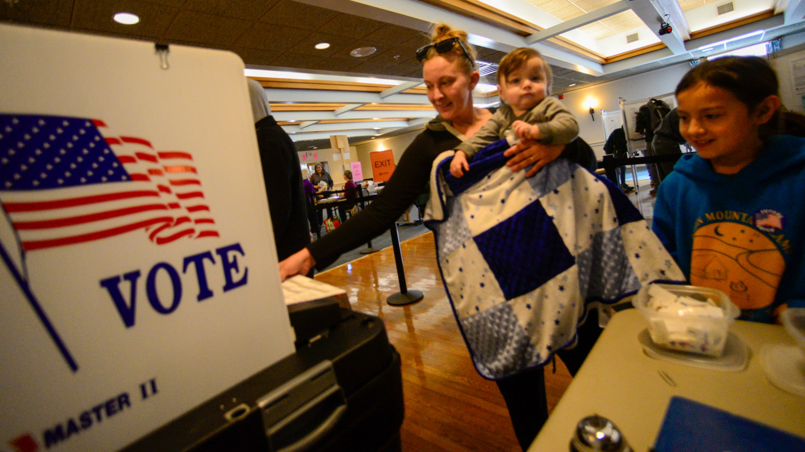 Caitlyn Person of Brattleboro, Vt., surrounded by her two children, Ellie Person, 9, and Wyatt Findlay-Person, 1, casts her ballot at the polling station in Brattleboro on Election Day on Tuesday, Nov. 5, 2024. (Kristopher Radder/The Brattleboro Reformer via AP)