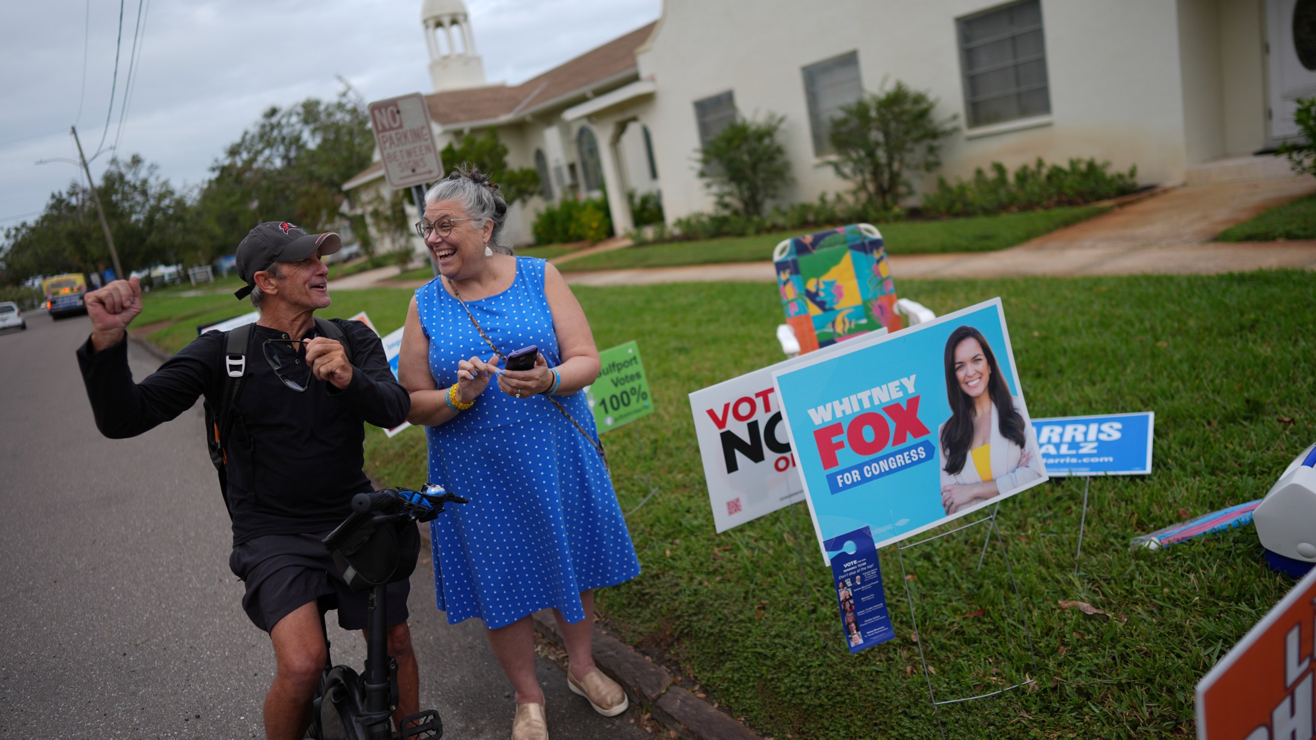 Trump supporter Barney Morin, left, cheers as Democratic poll greeter Lynn Akin helps him find his polling place so he can vote, outside a voting bureau at First United Methodist Church on Election Day, Tuesday, Nov. 5, 2024, in Gulfport, Fla. (AP Photo/Rebecca Blackwell)