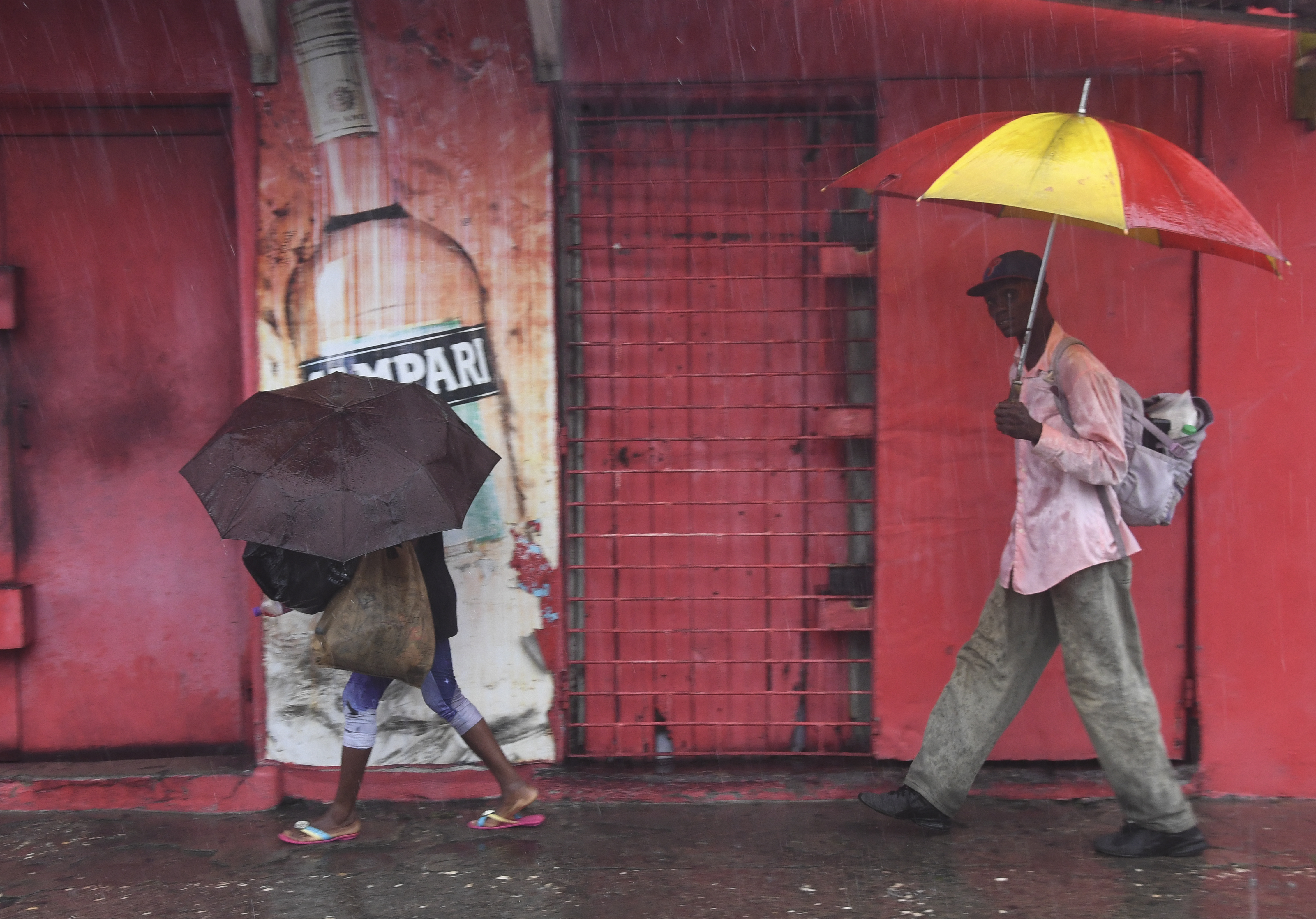 Pedestrians walk during rains brought on by tropical storm Rafael in Kingston, Jamaica, Tuesday, Nov. 5, 2024. (AP Photo/Collin Reid)